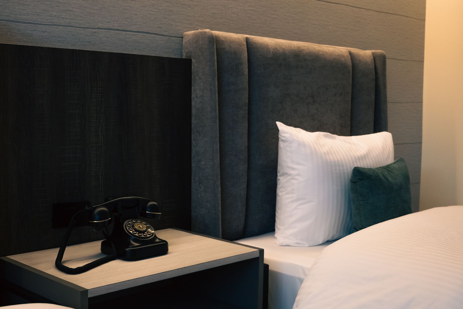 A hotel room with a bed , nightstand , and telephone.