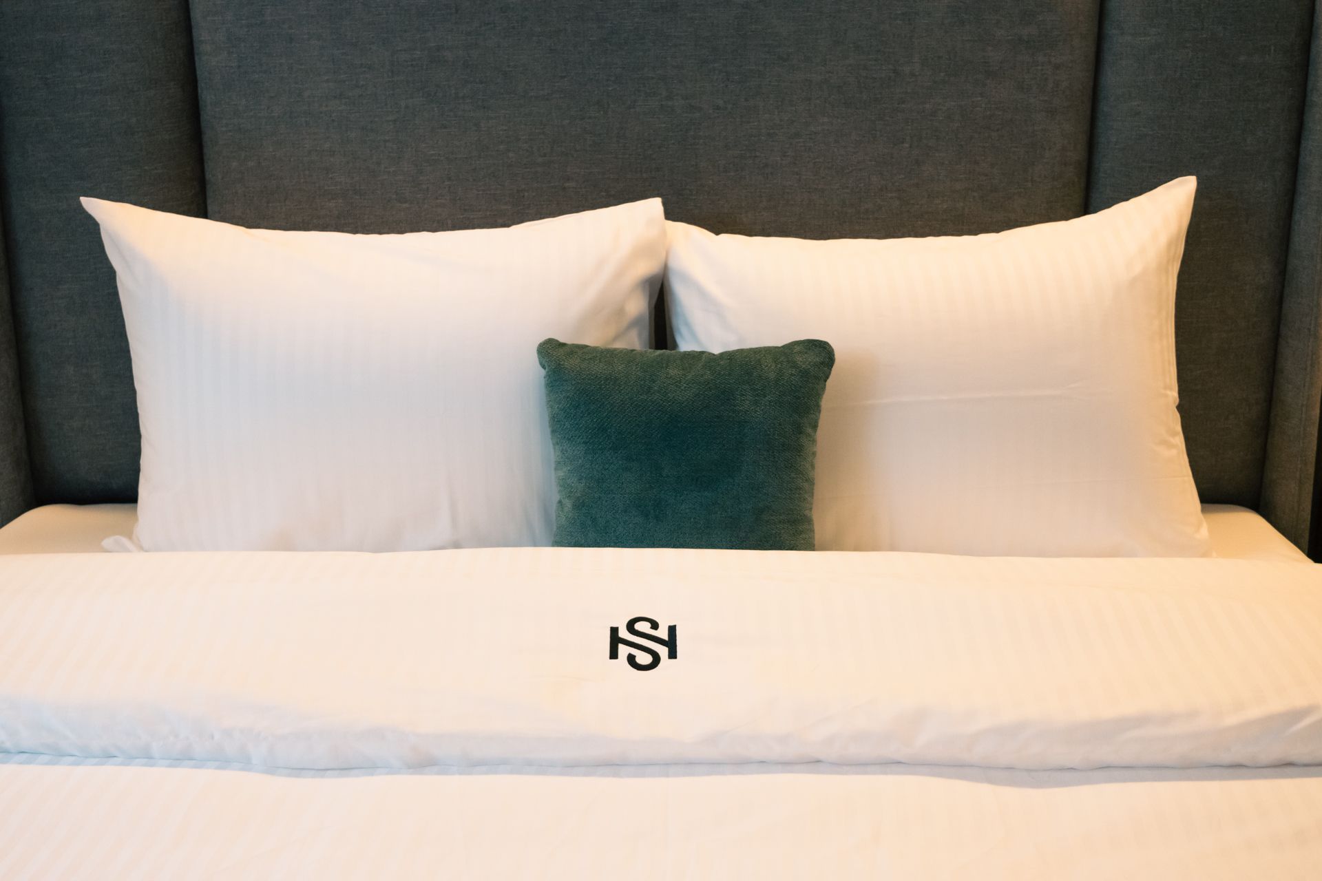 A bed with white pillows and a green pillow on it