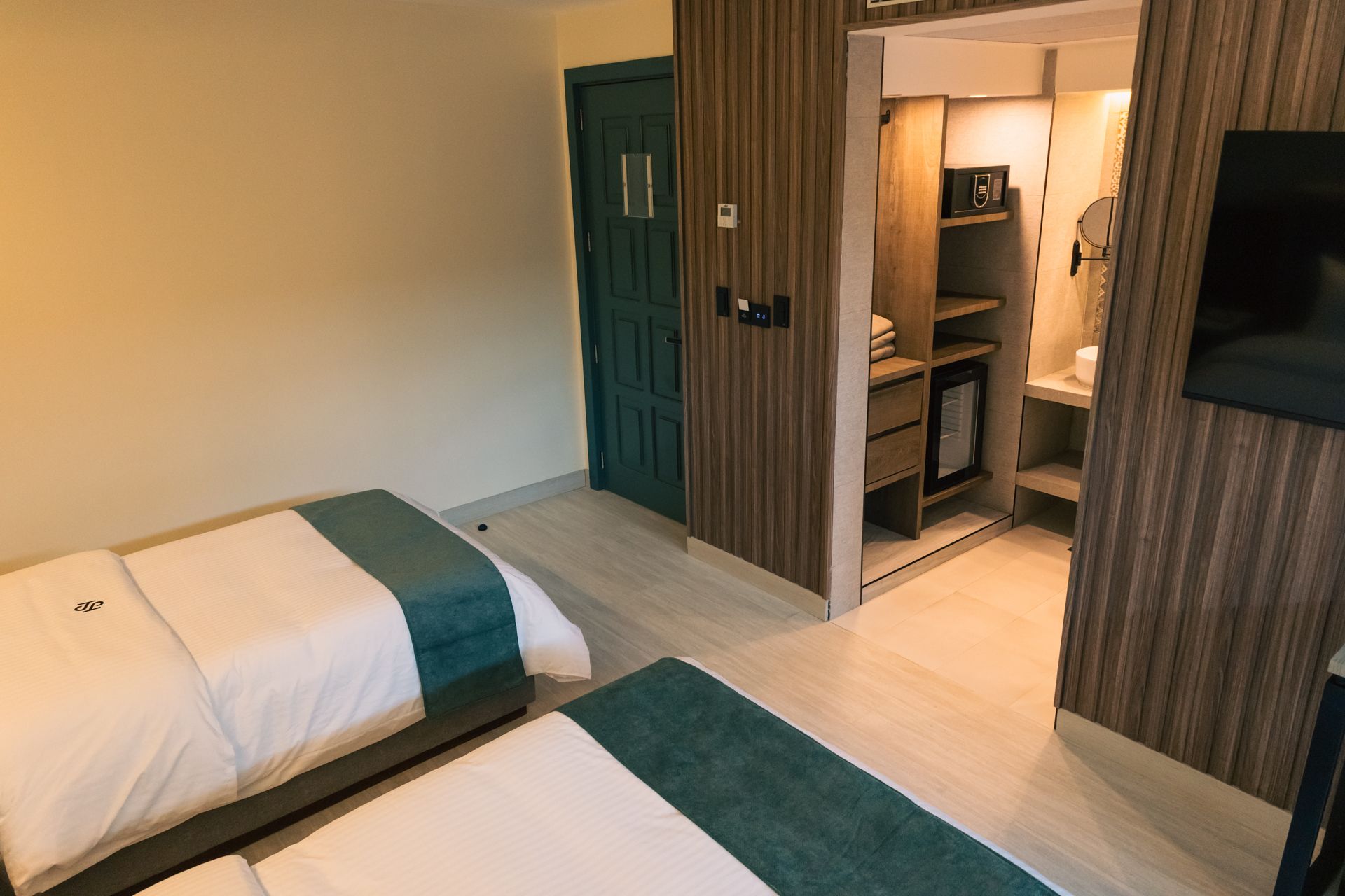 A hotel room with two beds , a closet and a television.