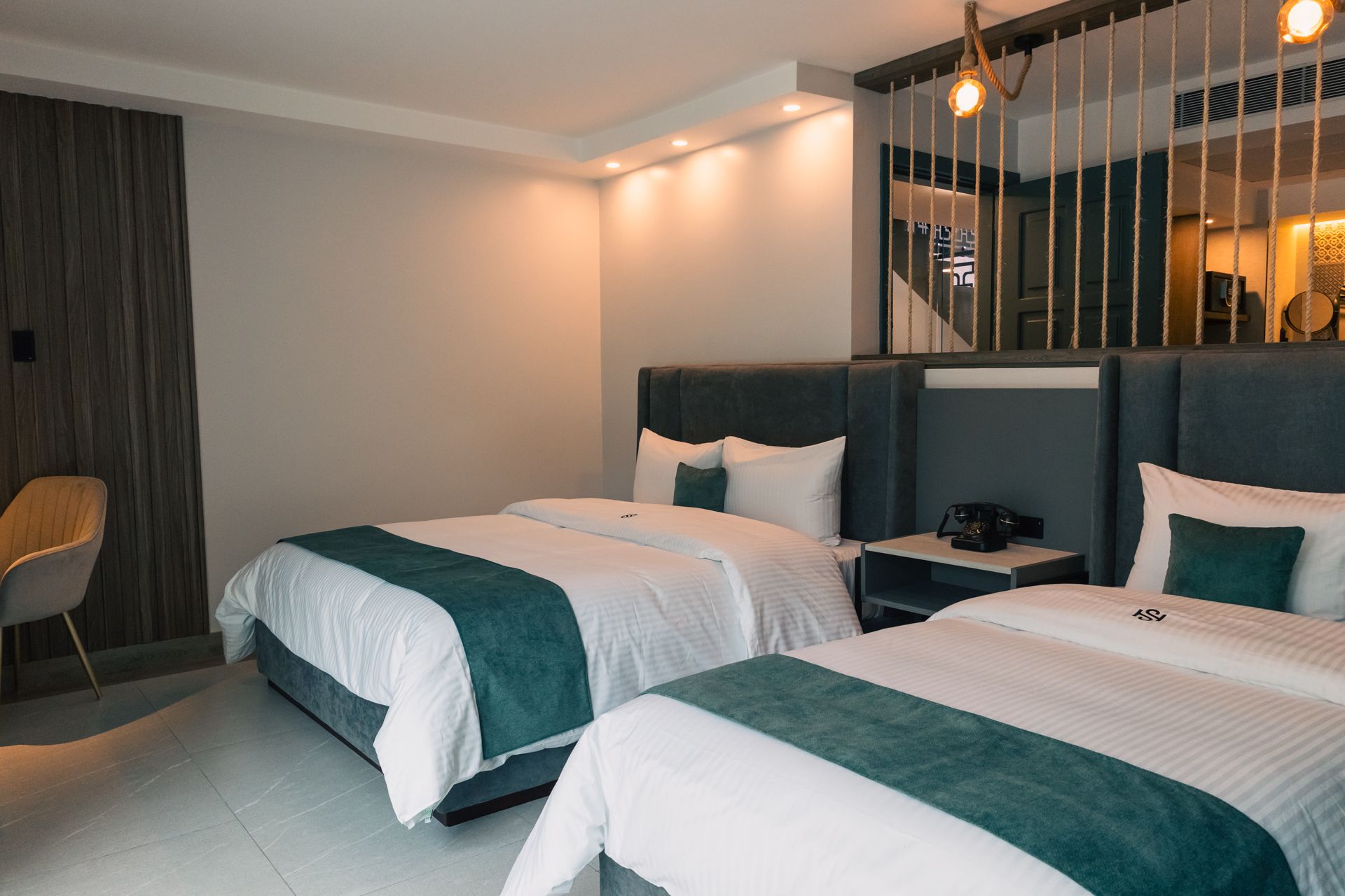 A hotel room with two beds and a chair.