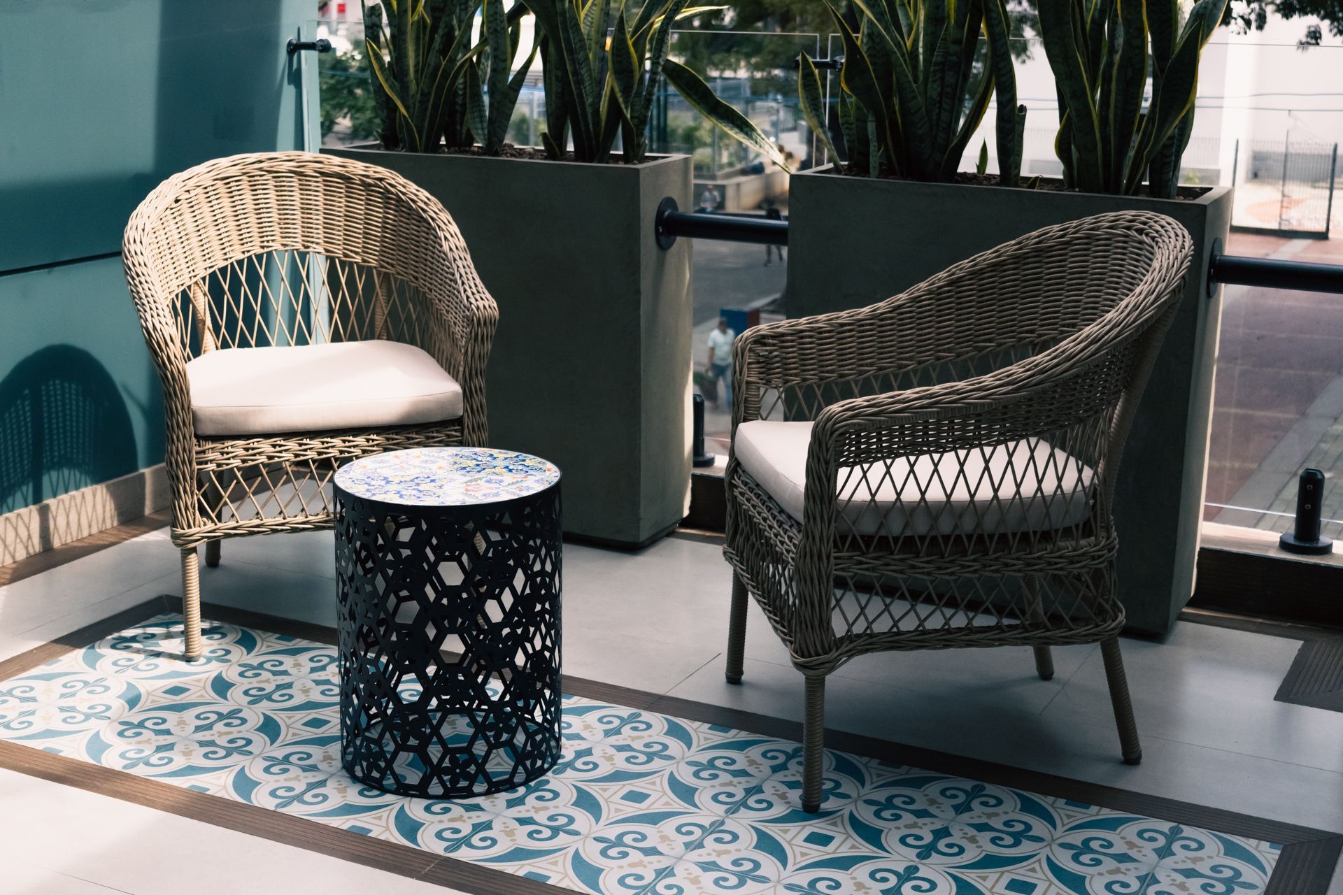 Two wicker chairs and a table are sitting on a tiled floor.