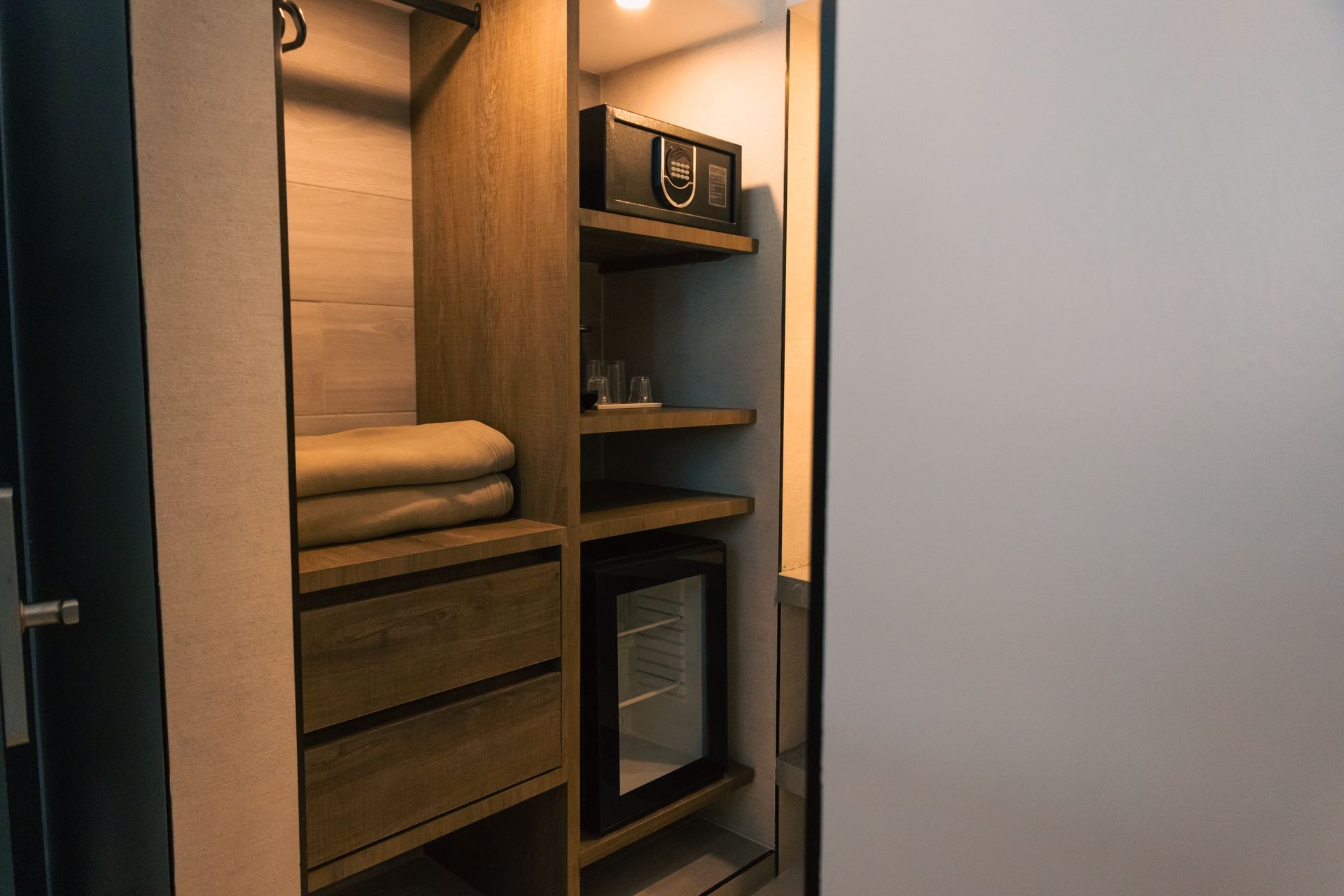 A hotel room with a walk in closet and a mini refrigerator.