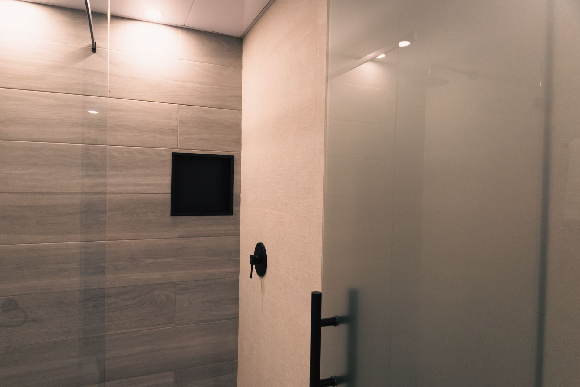 A bathroom with a walk in shower with a glass door.