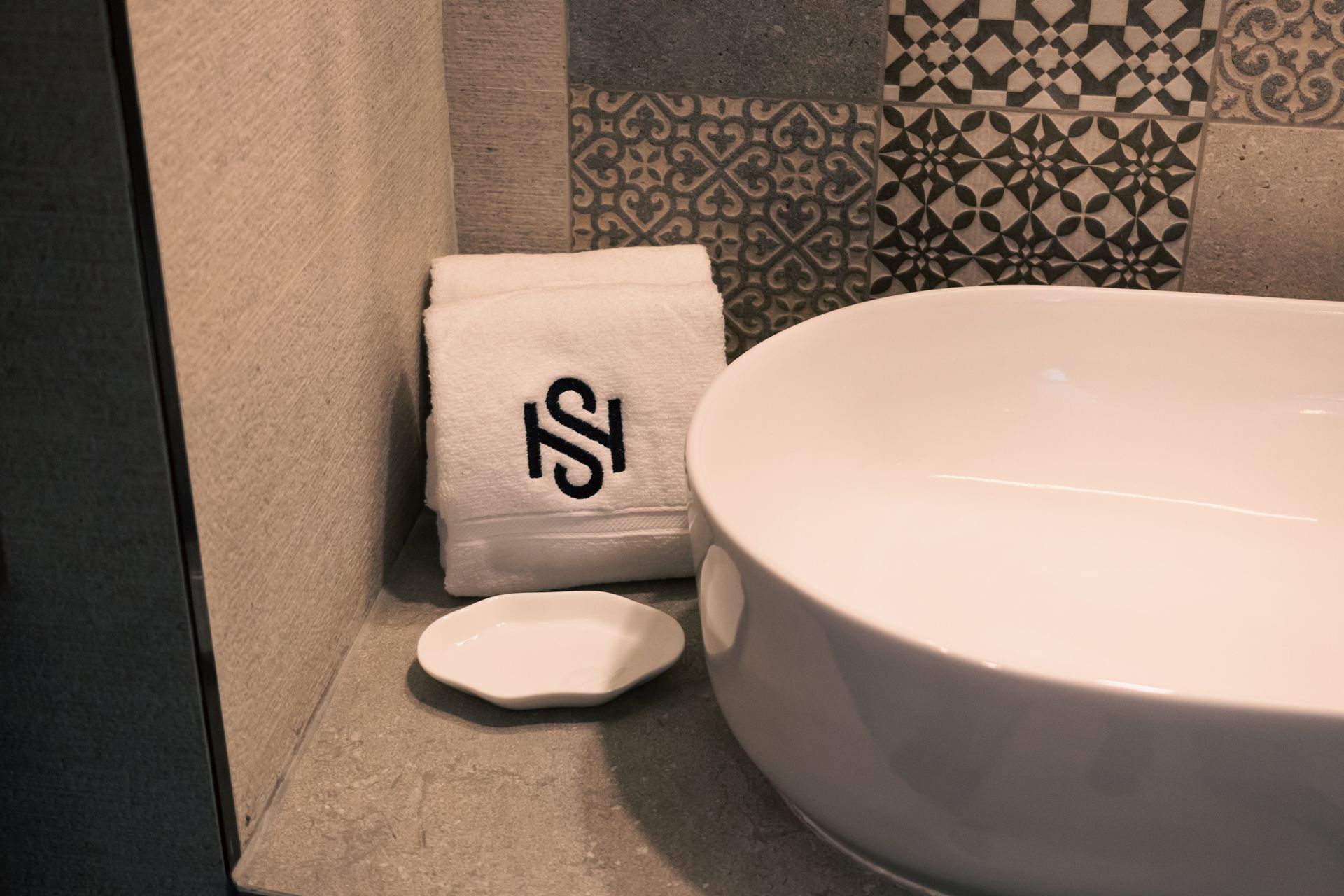 A bathroom with a sink and a towel with the letter s on it
