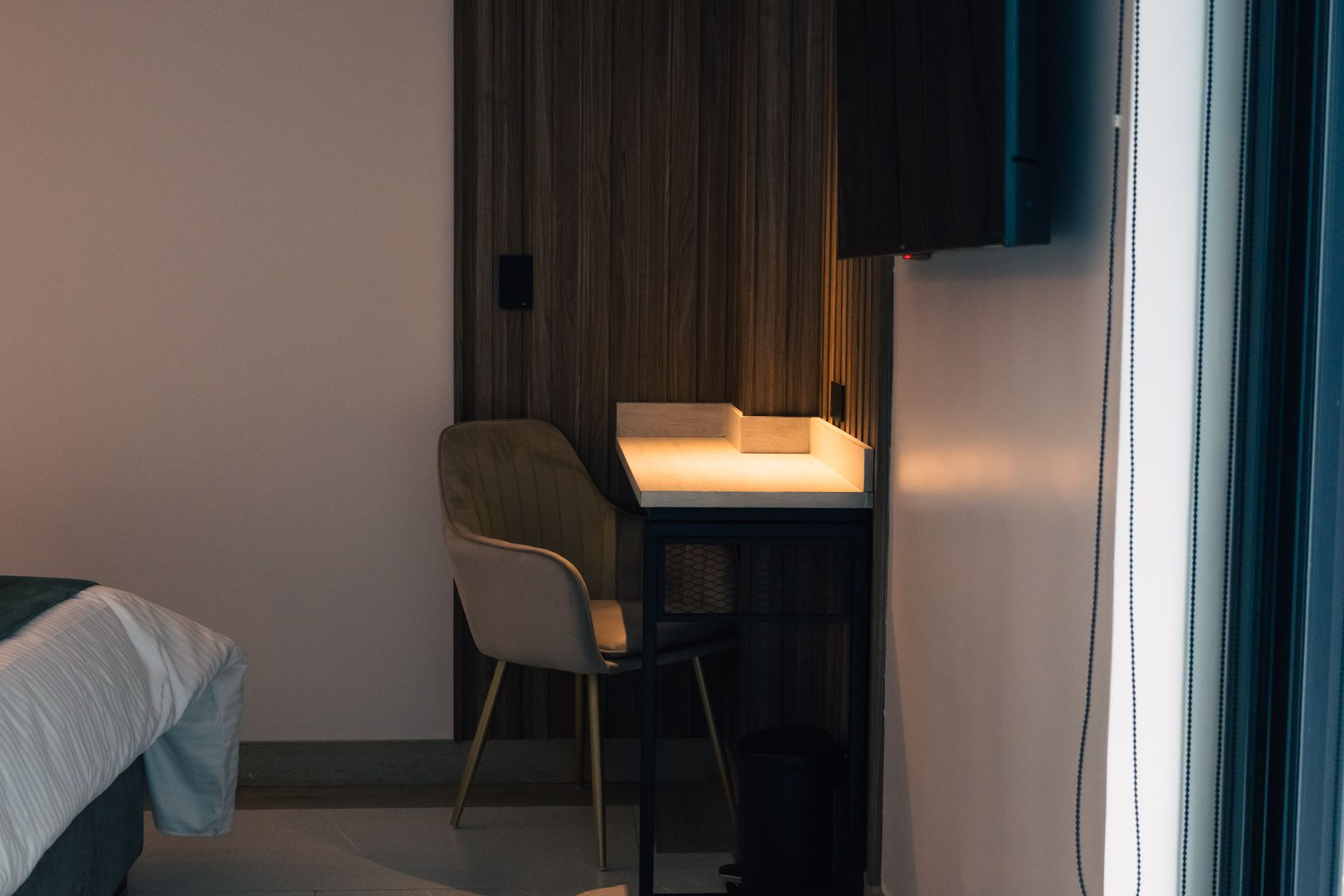 A hotel room with a bed , desk , chair and television.