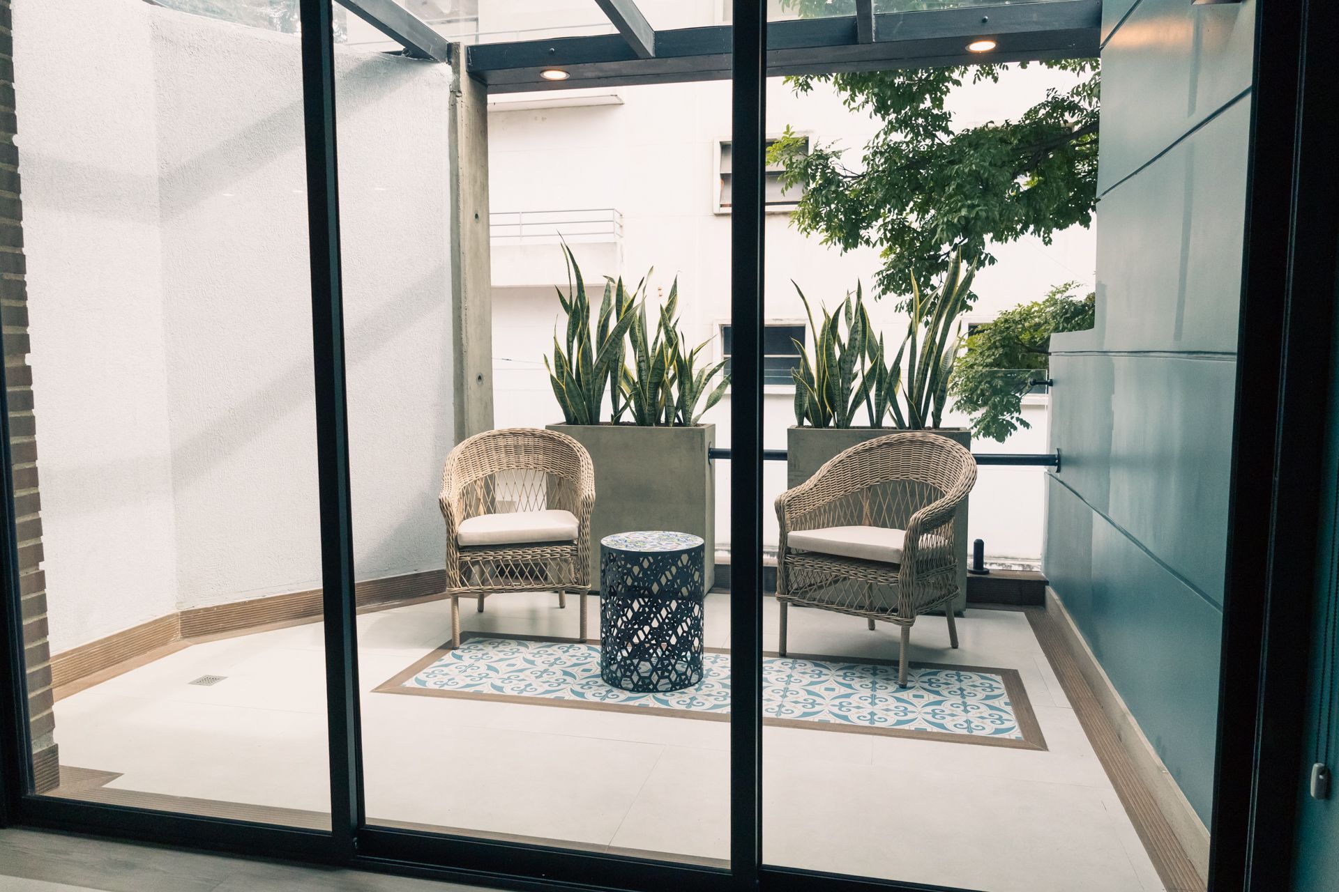 A patio with two chairs and a table in front of a sliding glass door.