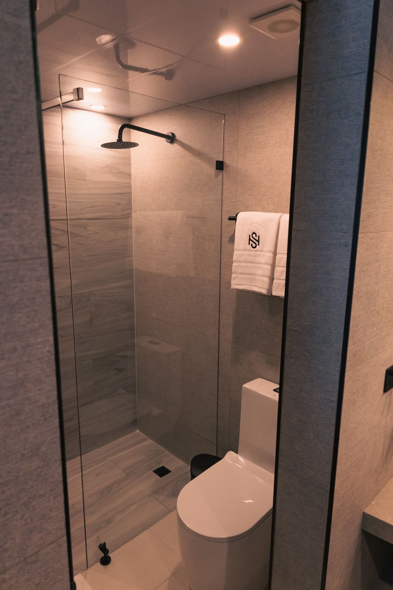 A bathroom with a toilet , shower and mirror.