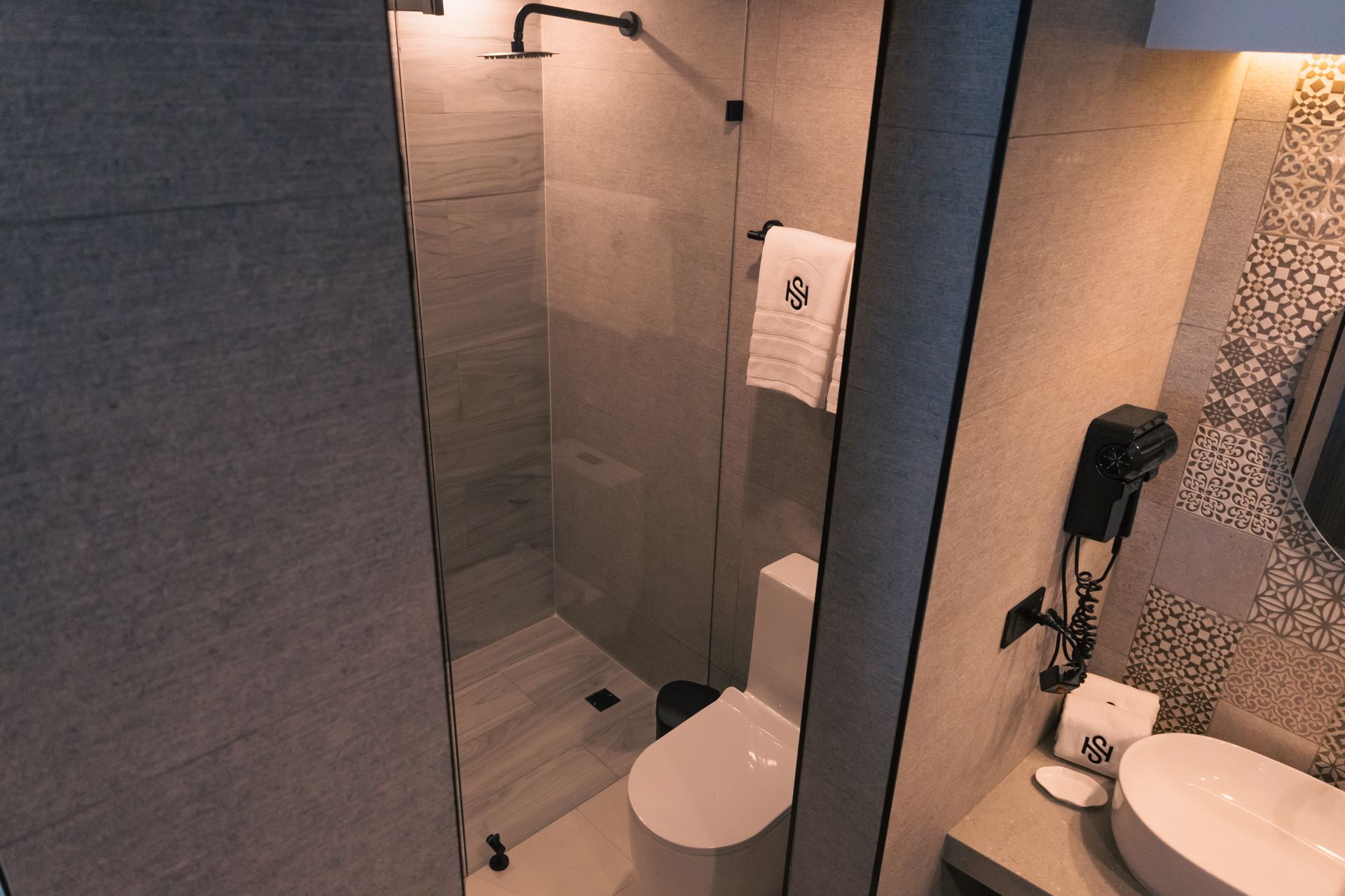 A bathroom with a toilet , sink and shower.