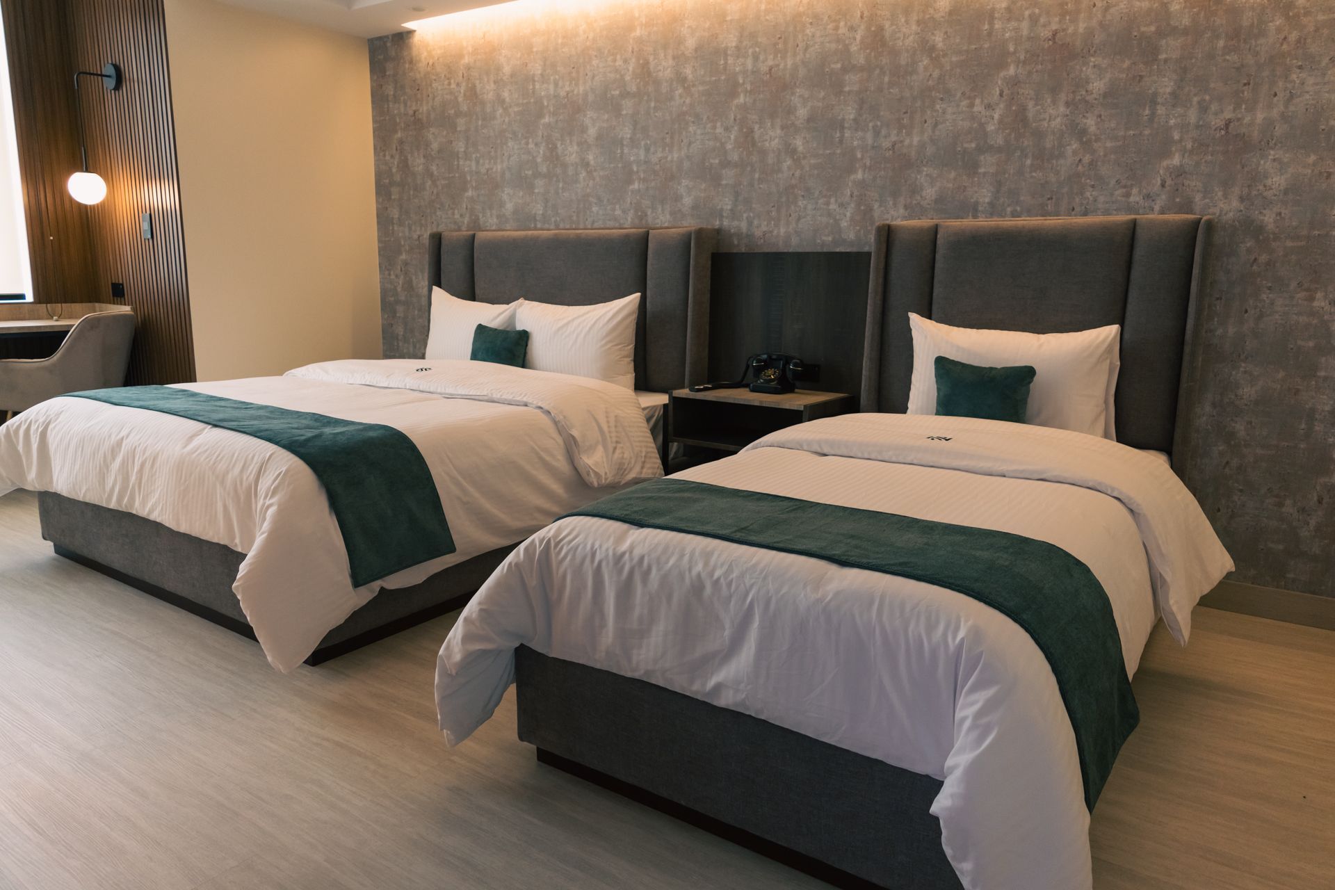 A hotel room with two beds and a desk.