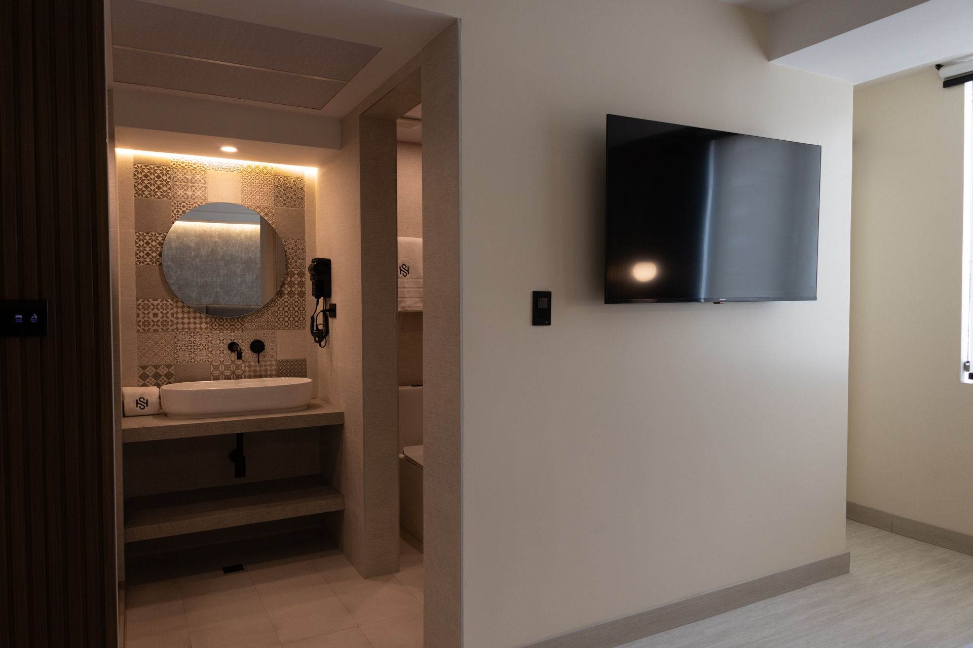 A bathroom with a sink and a flat screen tv on the wall.