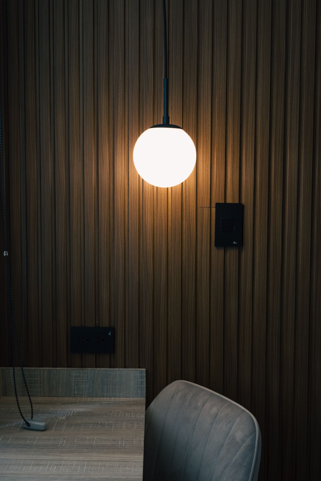A dining room with a table and chairs and a pendant light hanging from the ceiling.