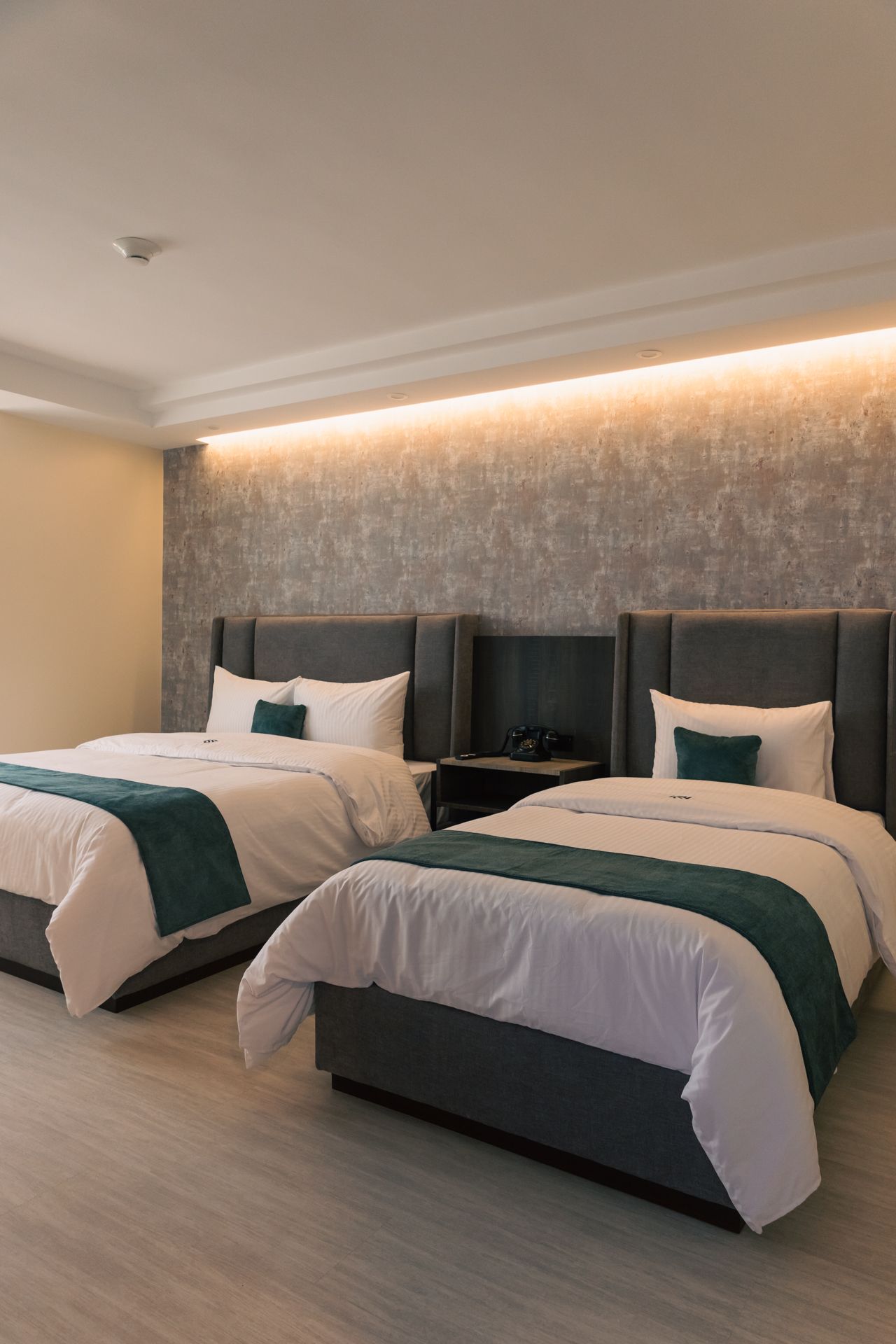 A hotel room with two beds and a nightstand.