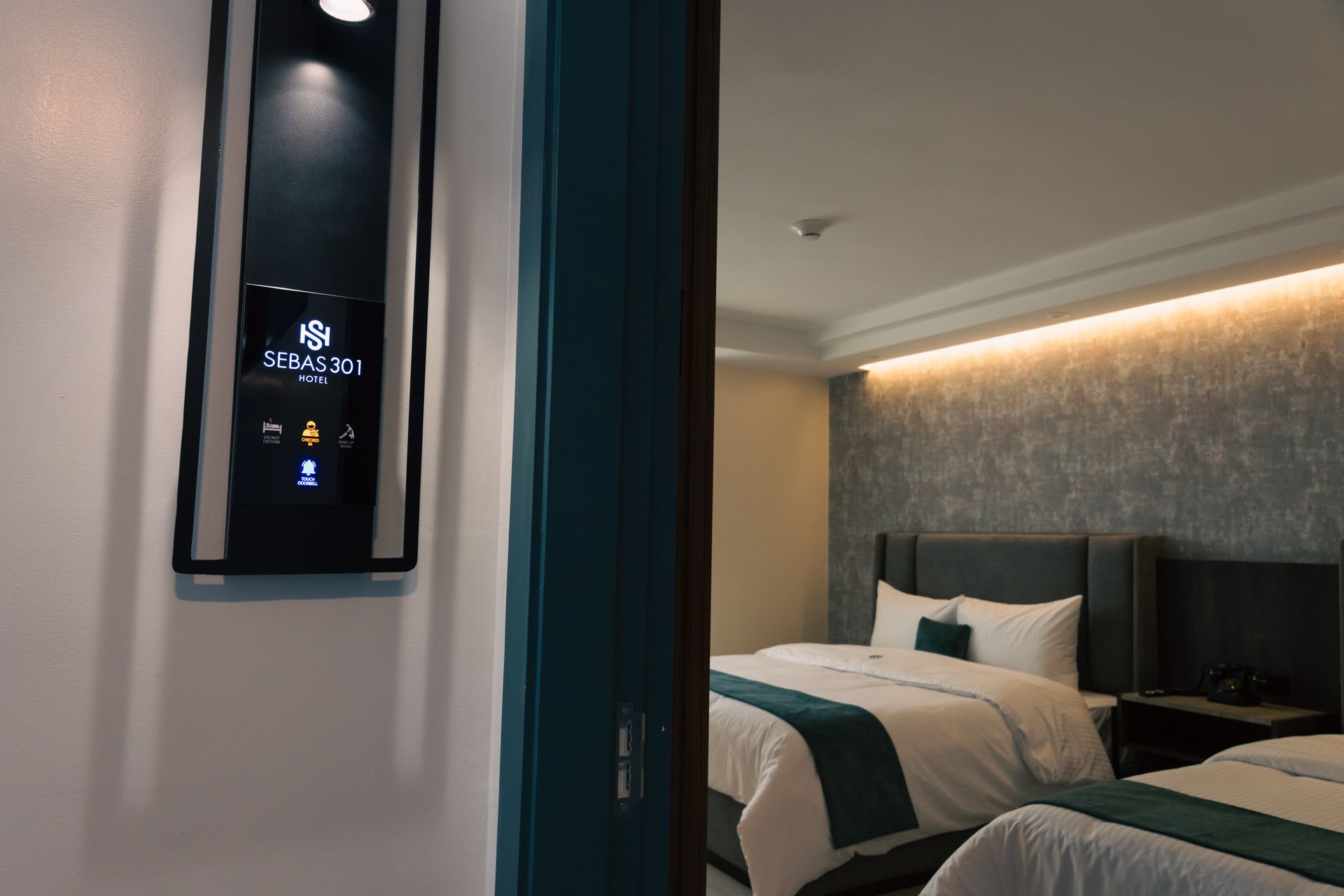 A hotel room with two beds and a thermostat on the wall.