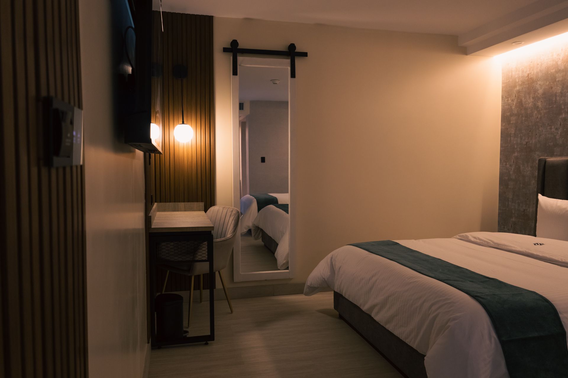 A hotel room with a king size bed , desk and mirror.