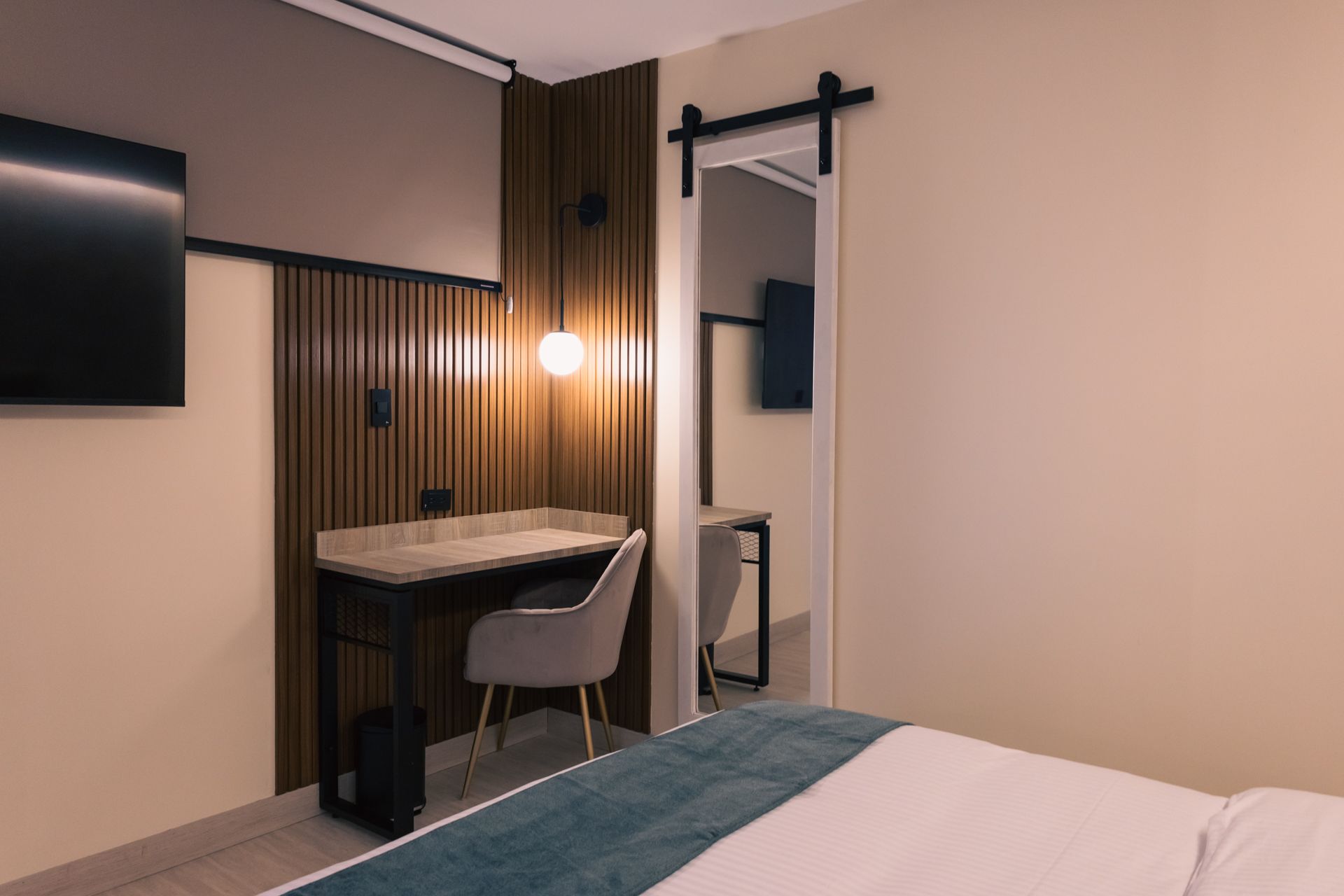 A hotel room with a bed , desk , chair and television.