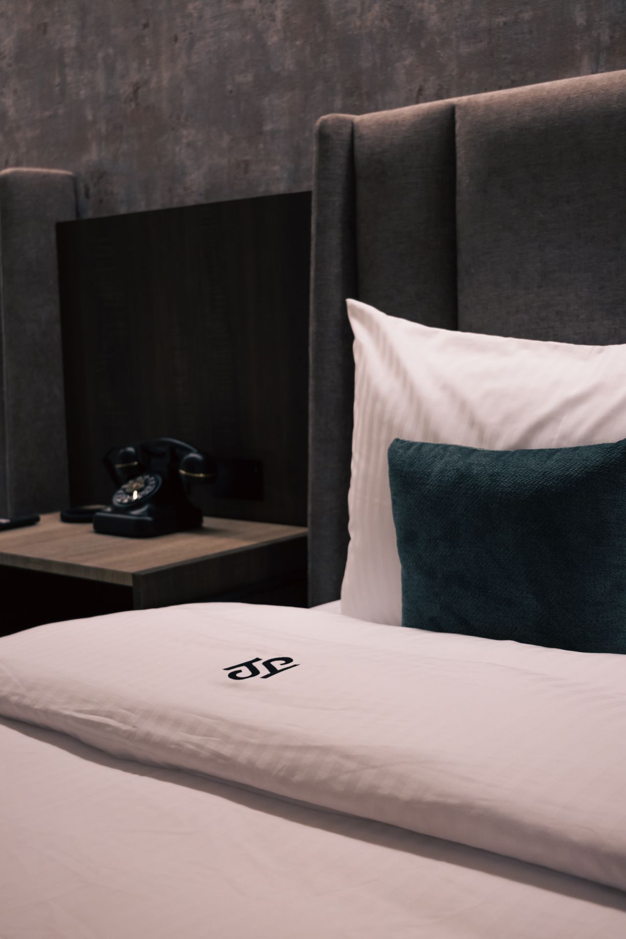 A hotel room with a bed and a phone on the nightstand