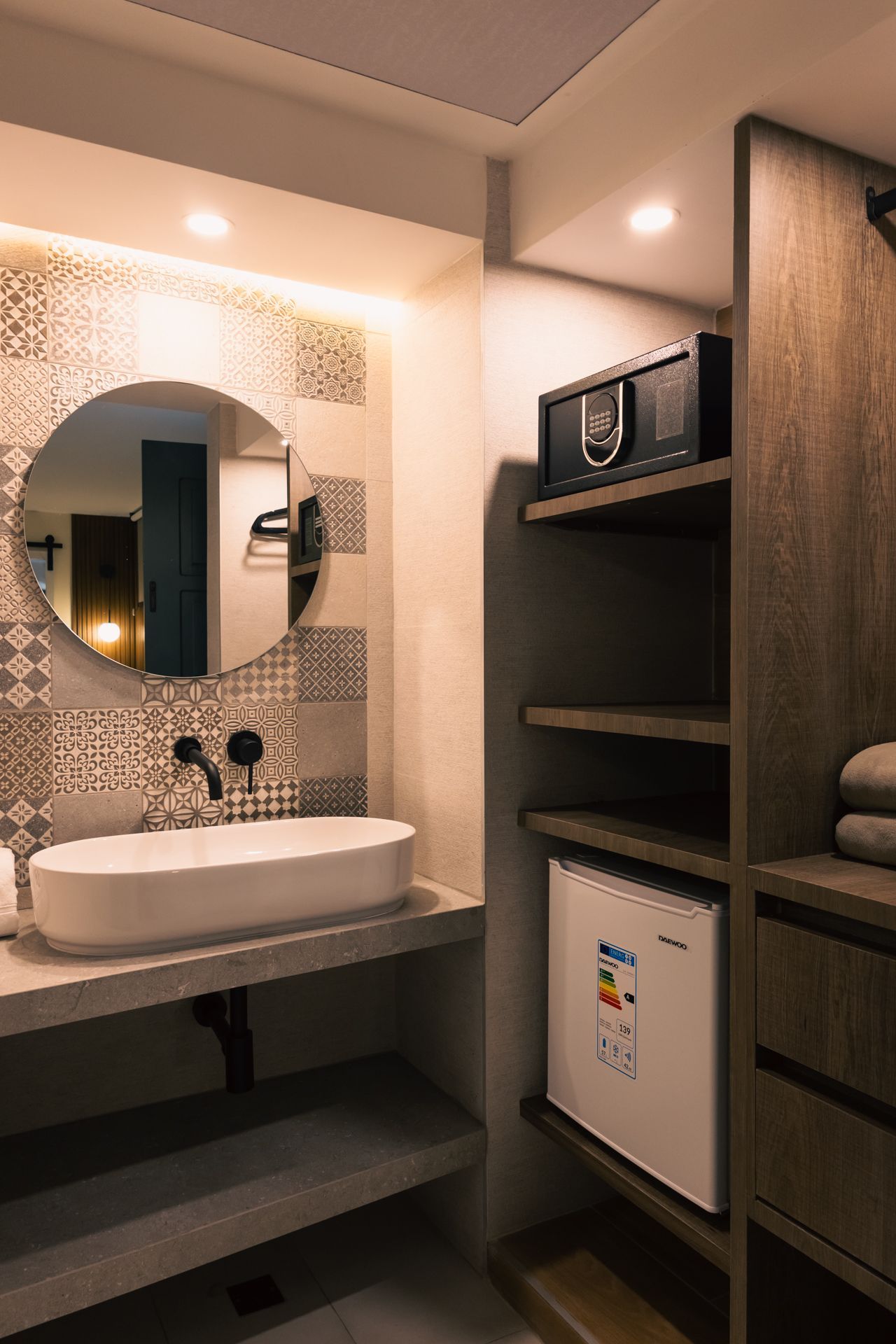 A bathroom with a sink , mirror , fridge and microwave.
