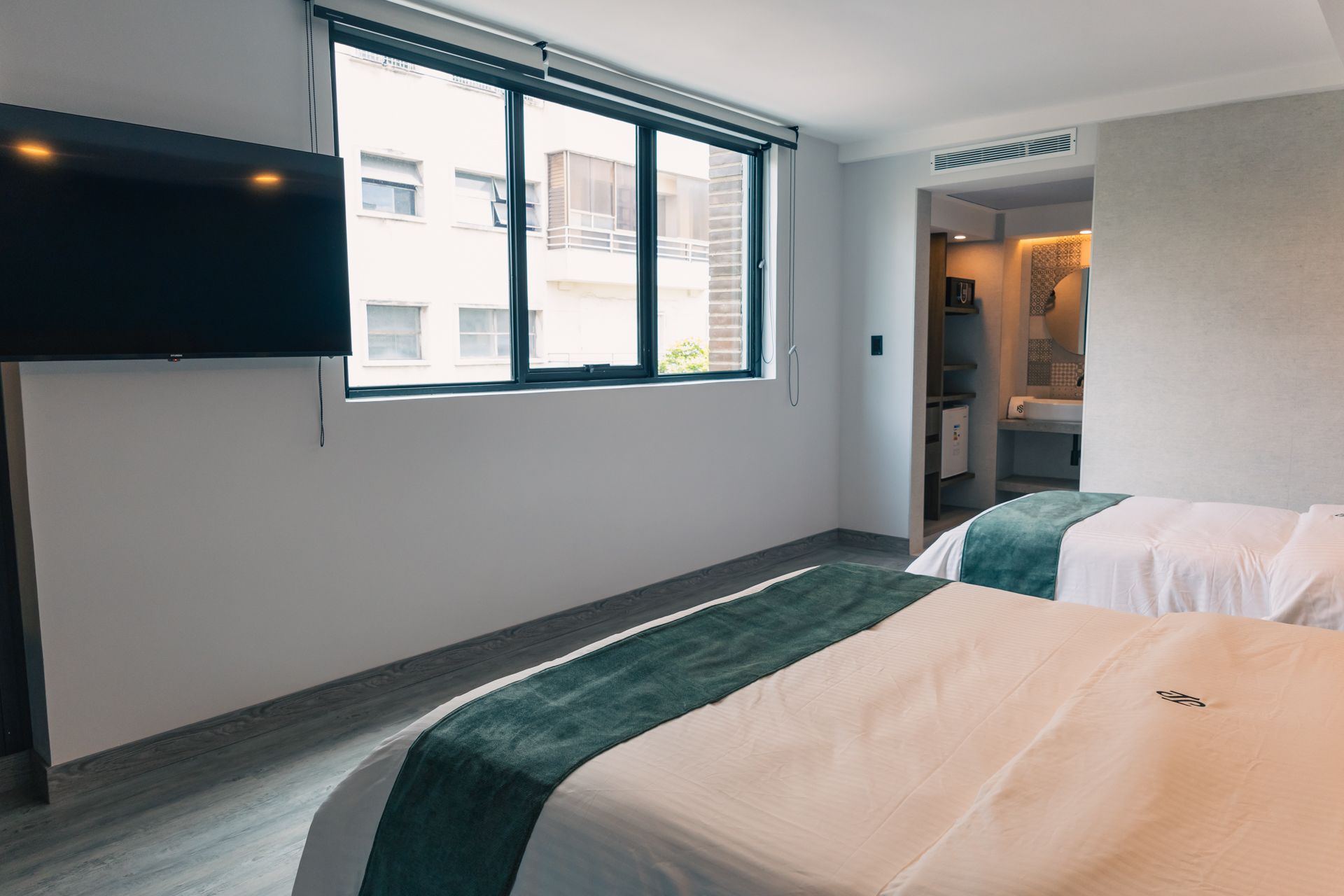 A hotel room with two beds and a flat screen tv.