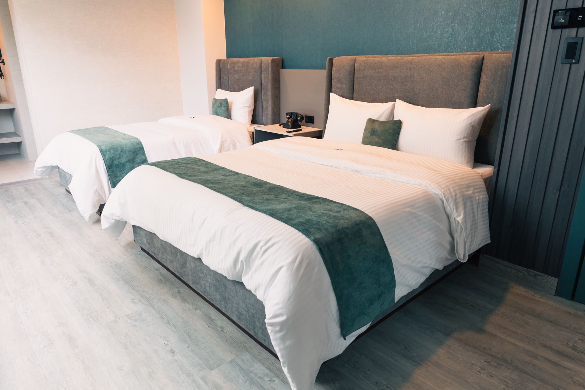 A hotel room with two beds and a blue wall.