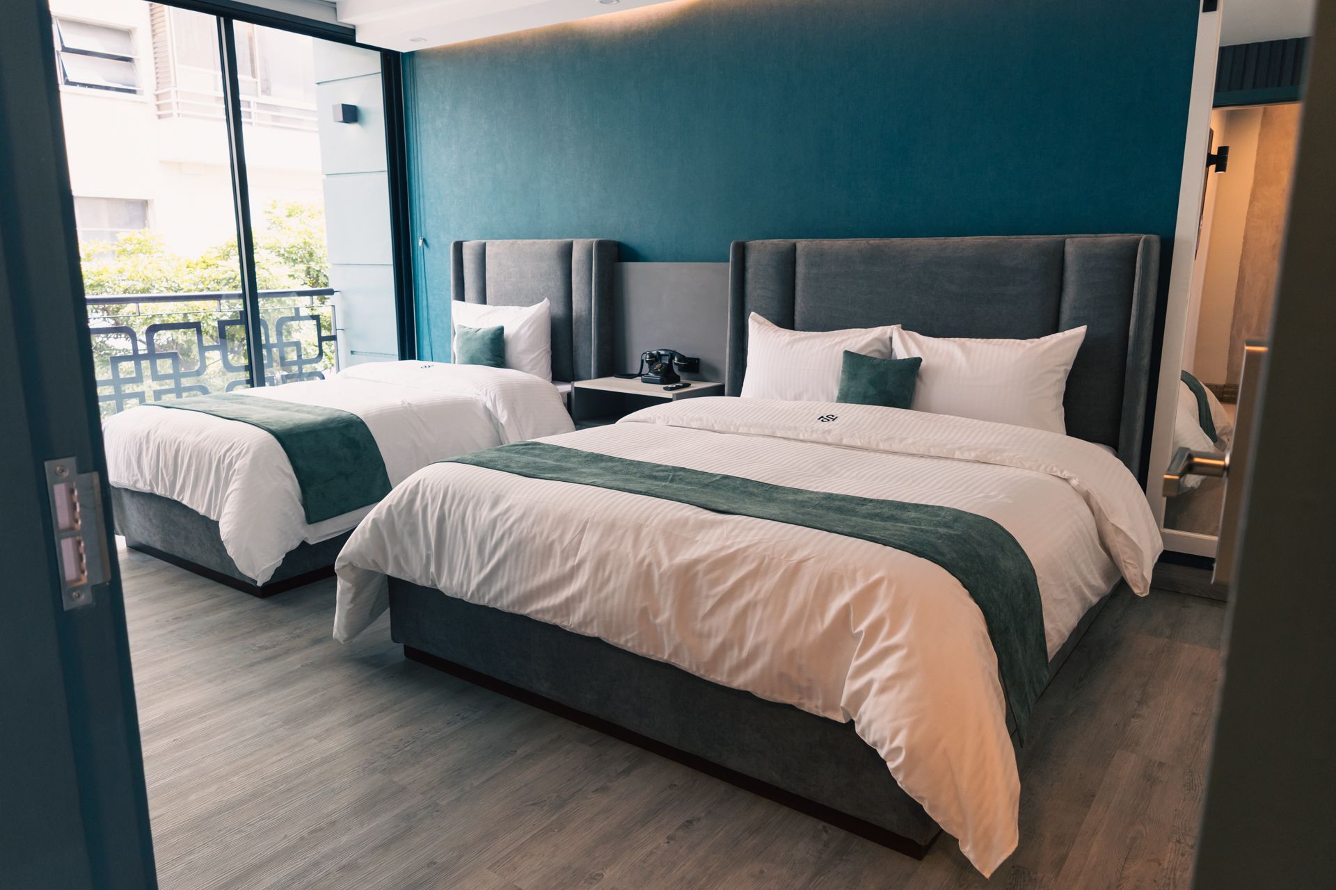 A hotel room with two beds and a balcony.