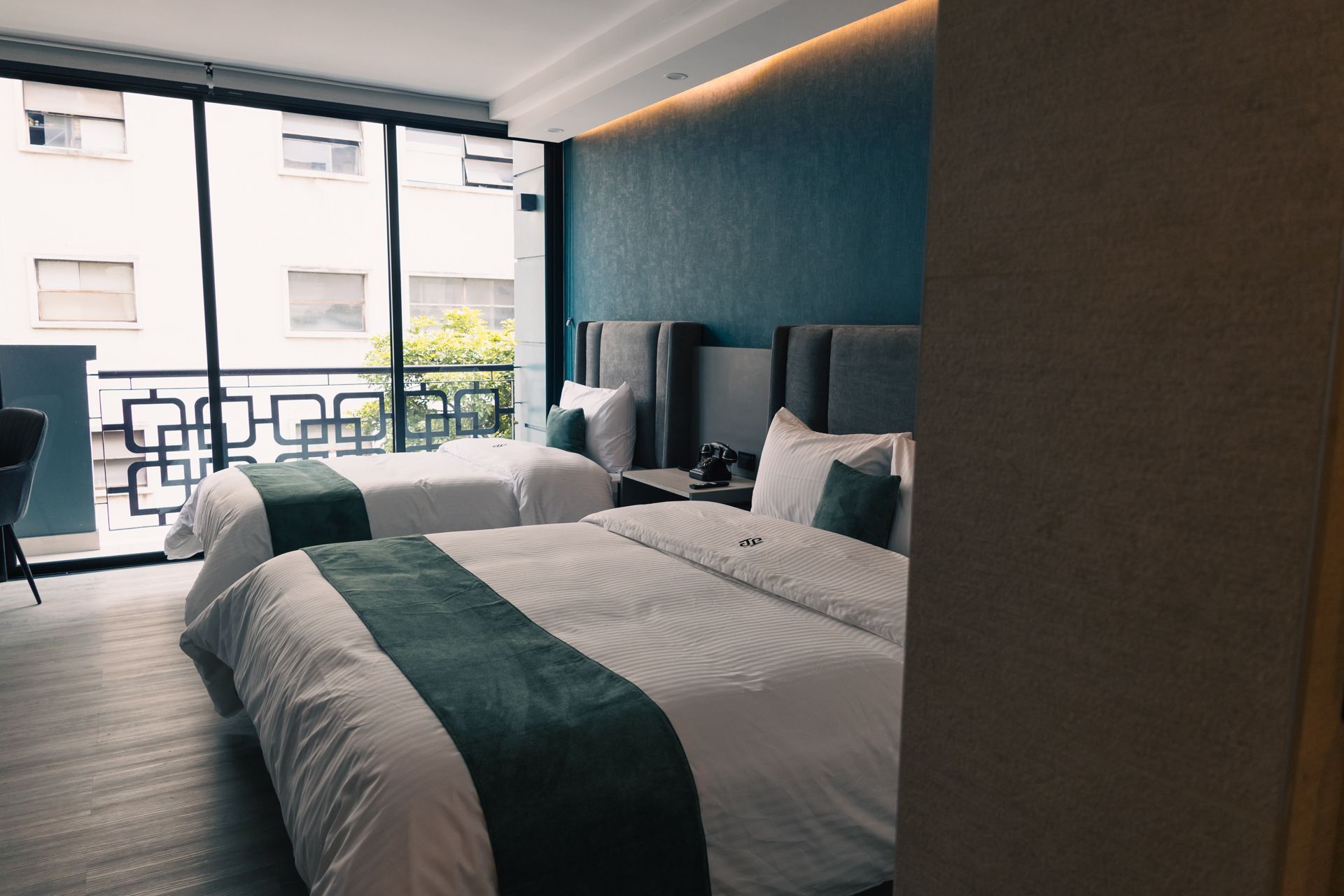 A hotel room with two beds and a balcony.