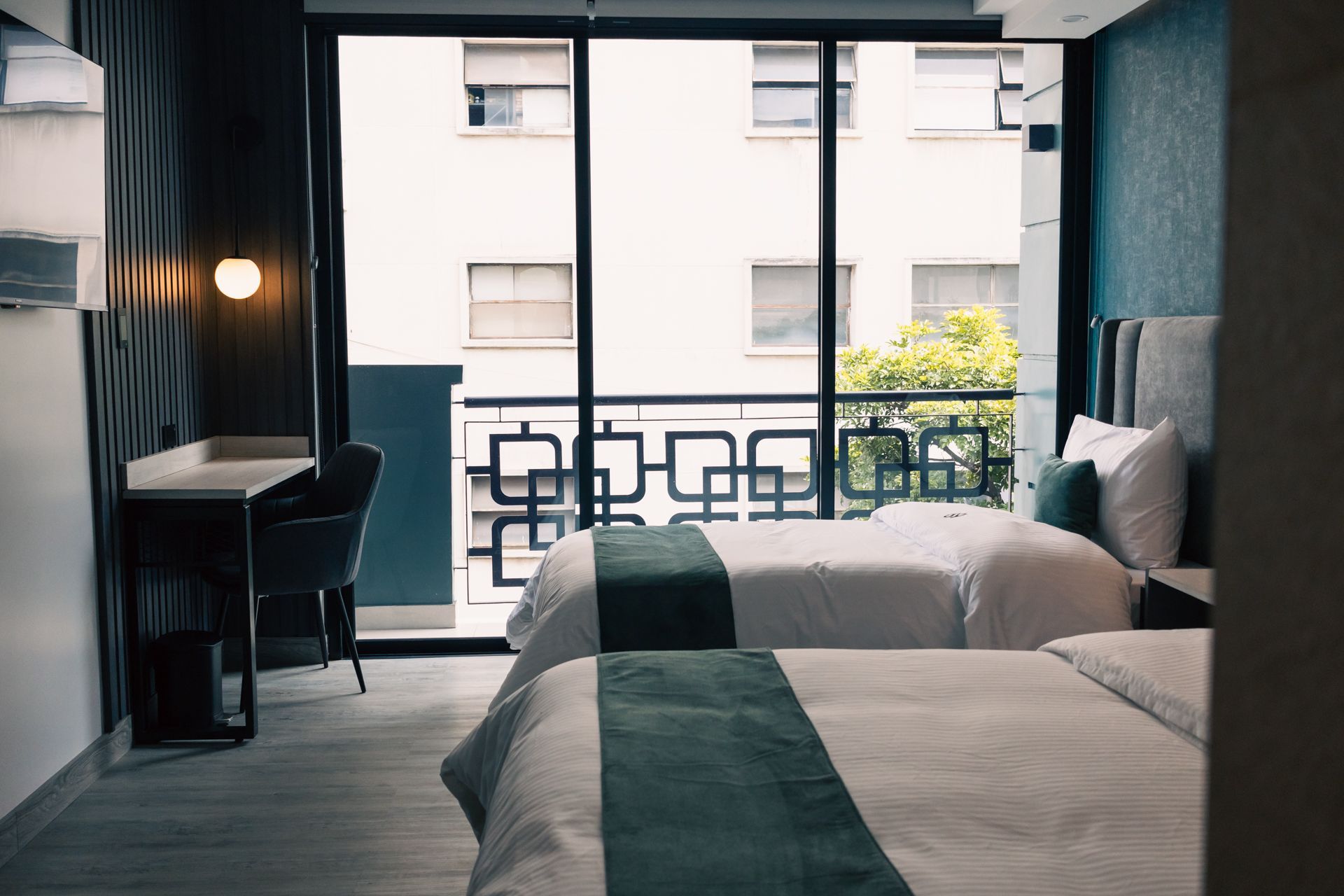 A hotel room with two beds , a desk and a balcony.