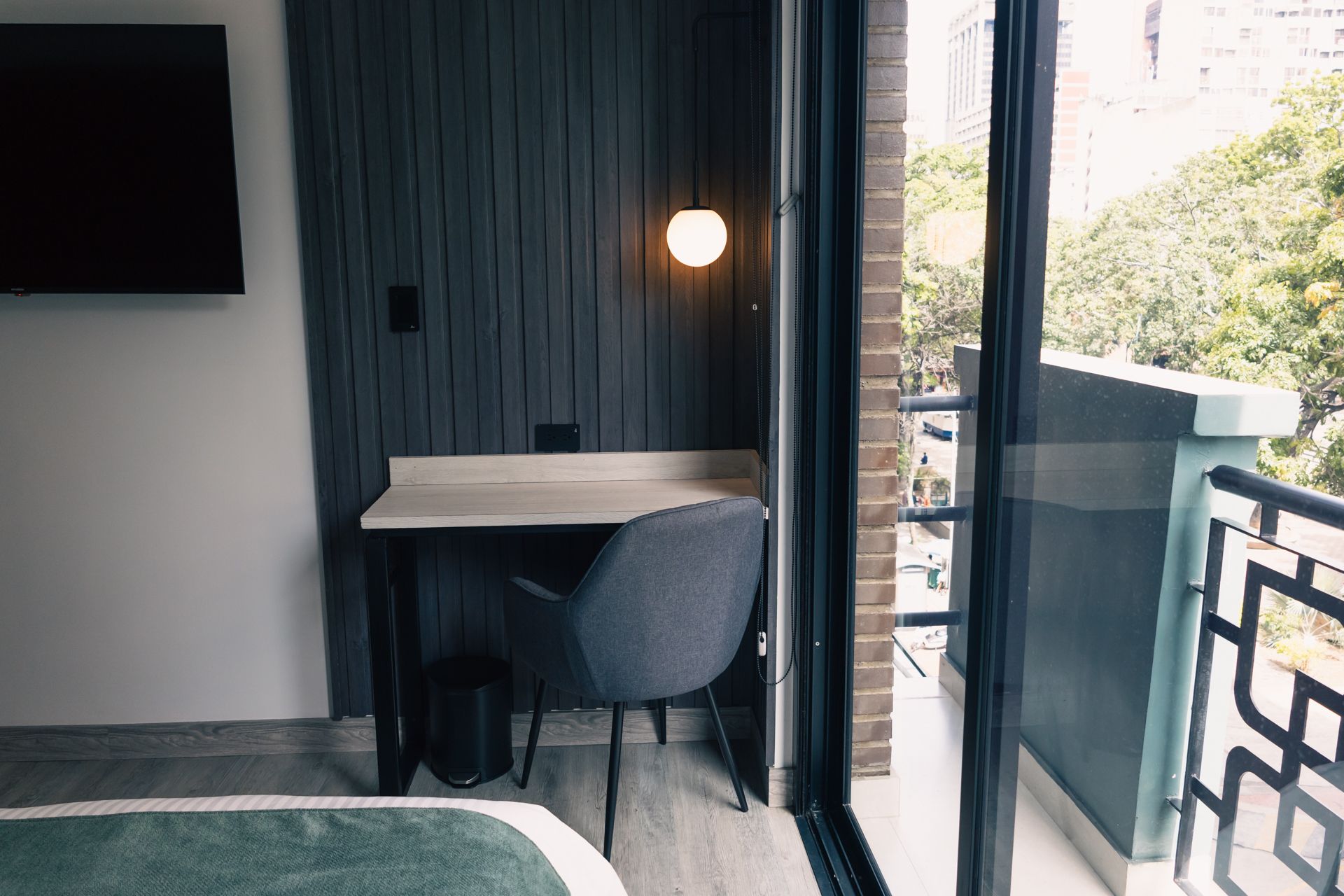 A hotel room with a desk , chair and television.