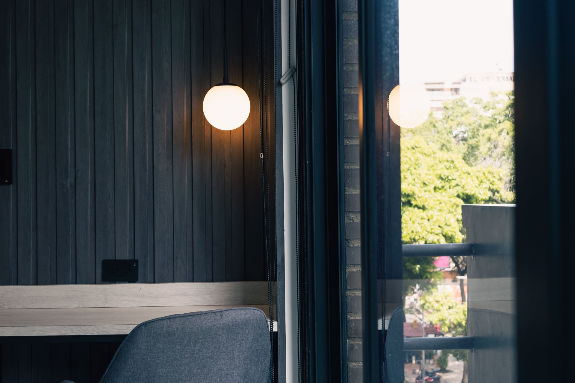 A room with a desk and chair and a window with a view of trees.