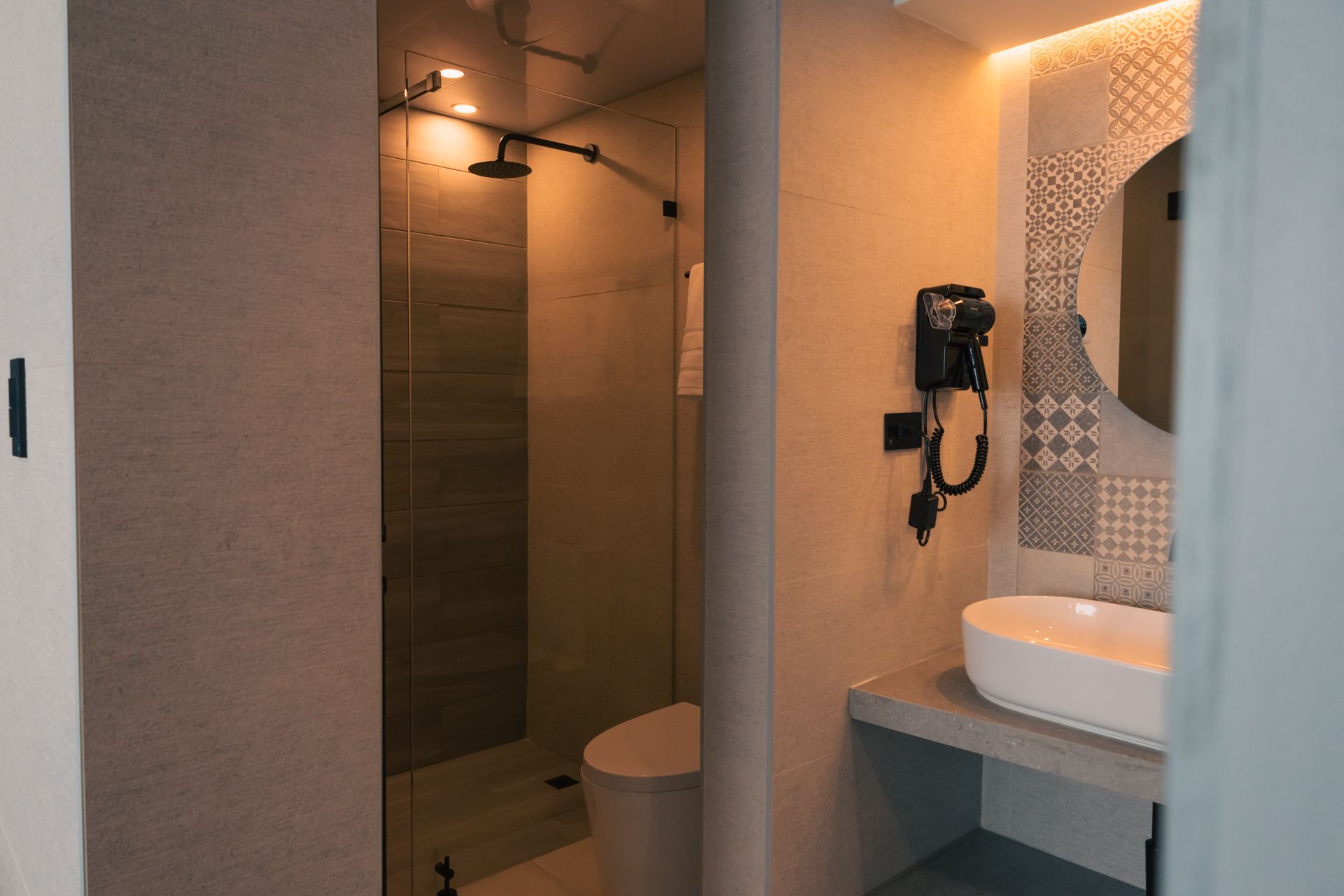 A bathroom with a toilet , sink , mirror and shower.