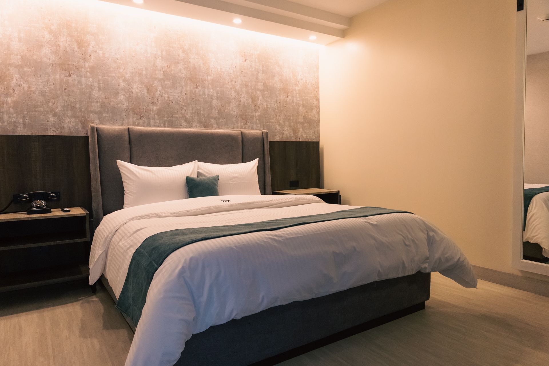 A hotel room with a king size bed and a mirror.