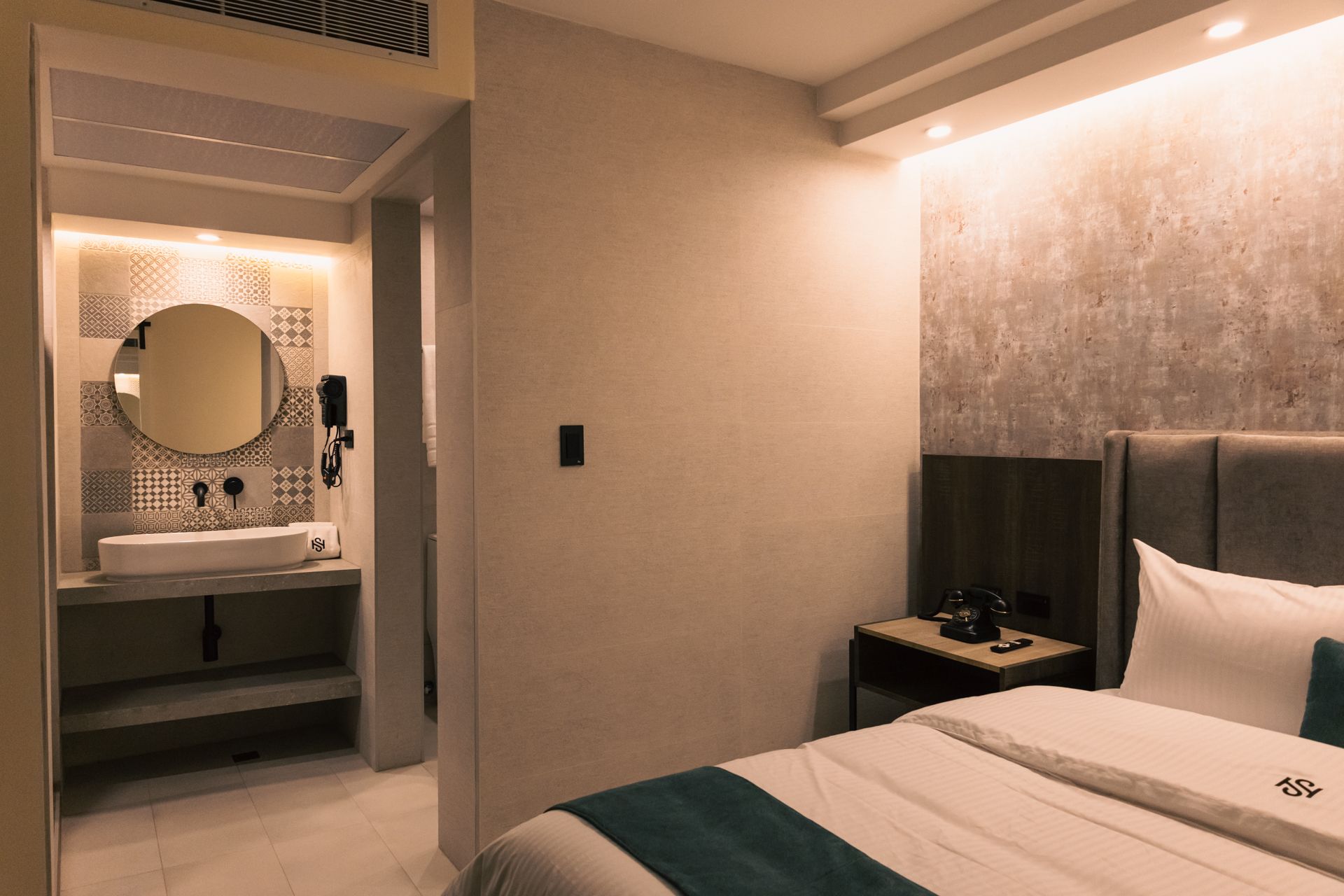 A hotel room with a bed , sink and mirror.