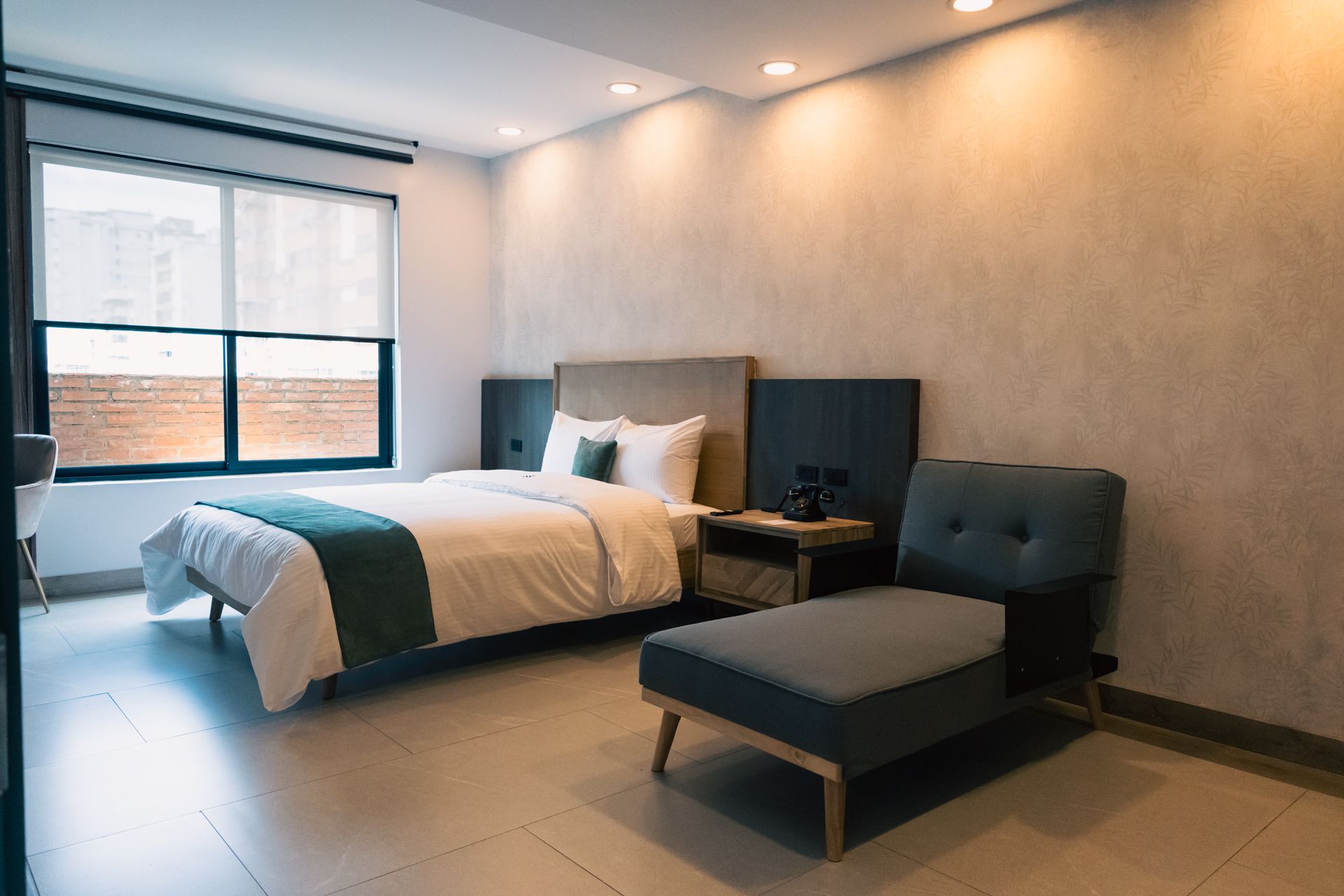 A hotel room with a bed , chair and window.