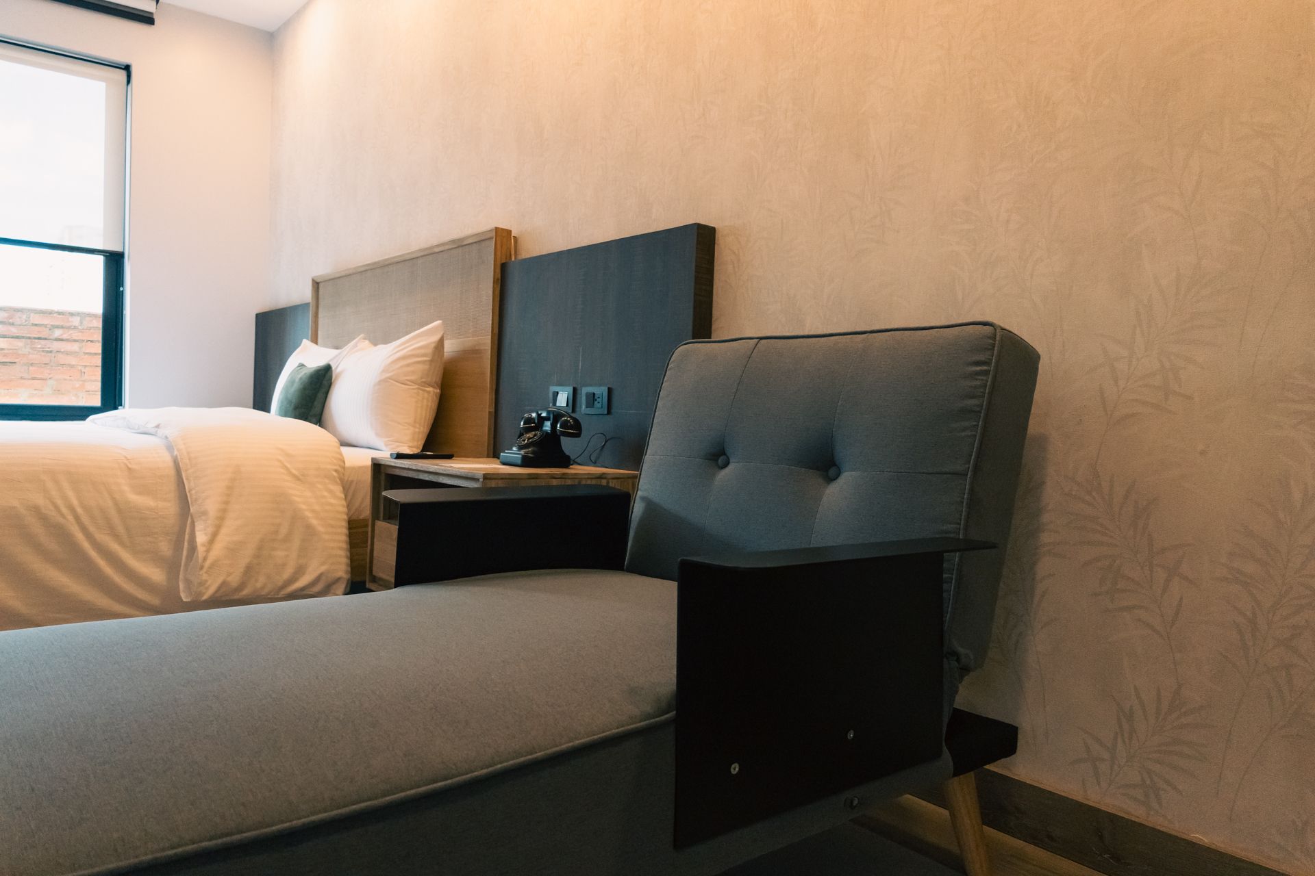 A hotel room with a bed , chair and nightstand.