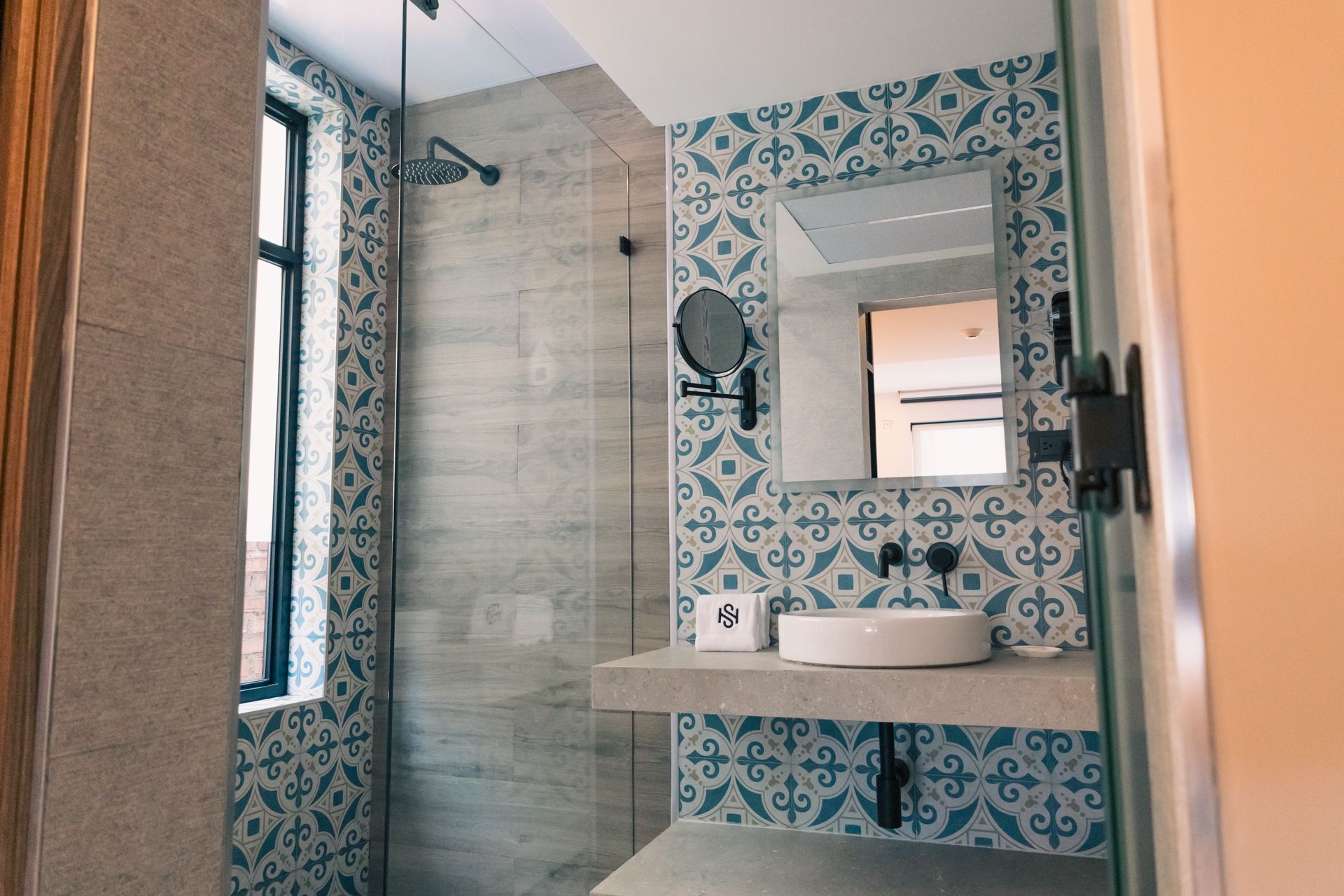 A bathroom with a sink , mirror and shower.