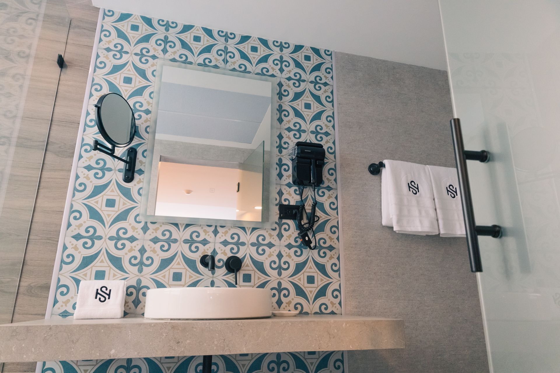 A bathroom with a sink , mirror and towels.
