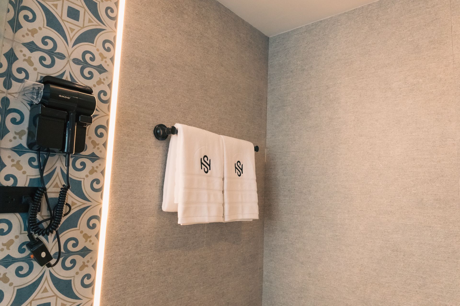 A bathroom with a hair dryer and towels hanging on the wall.