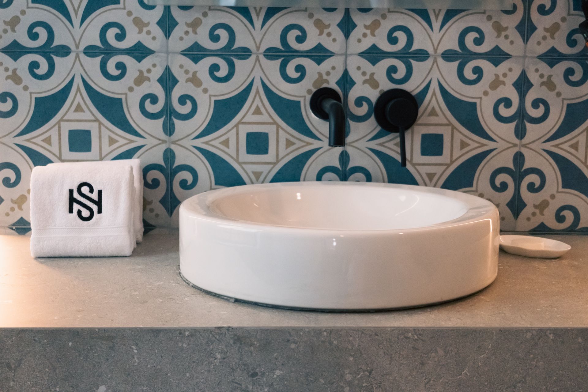 A bathroom with a sink and a towel with the letter s on it