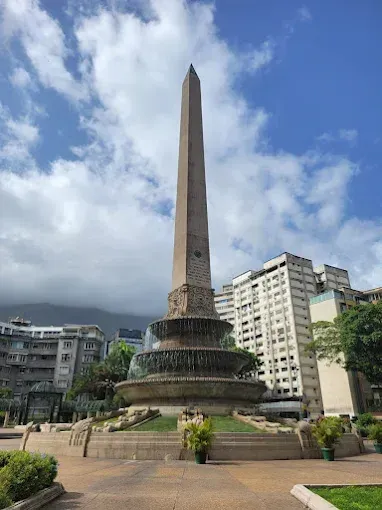 There is a large obelisk in the middle of a park.
