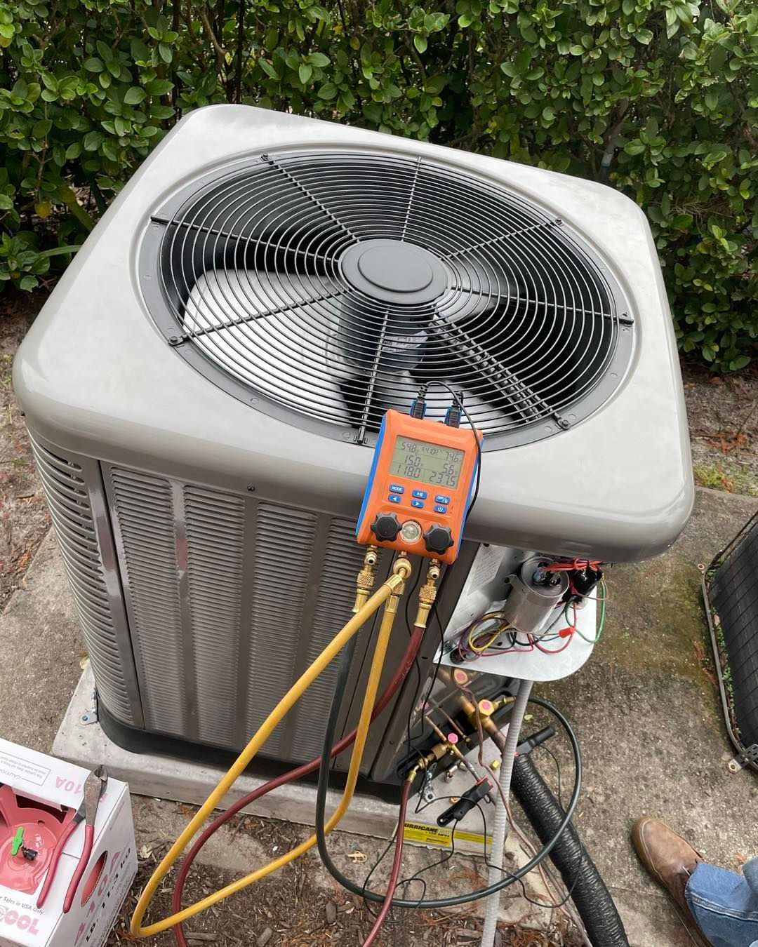 an air conditioner is being serviced by a technician .