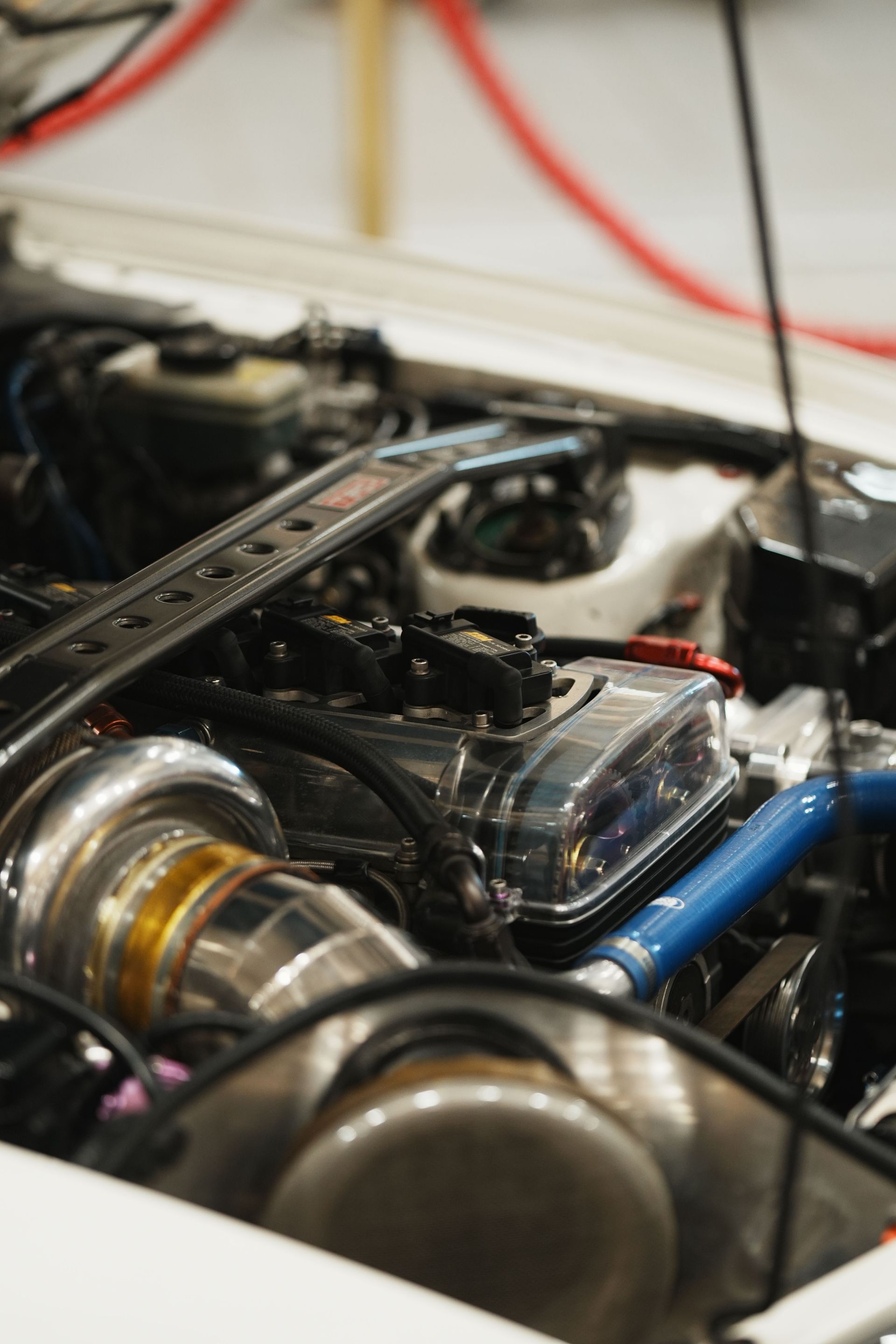 Close-up of a modified car engine bay with shiny metal parts and blue hoses