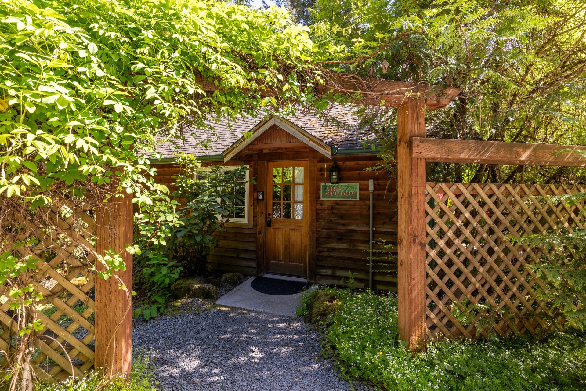 A small log cabin with a green roof is surrounded by trees
