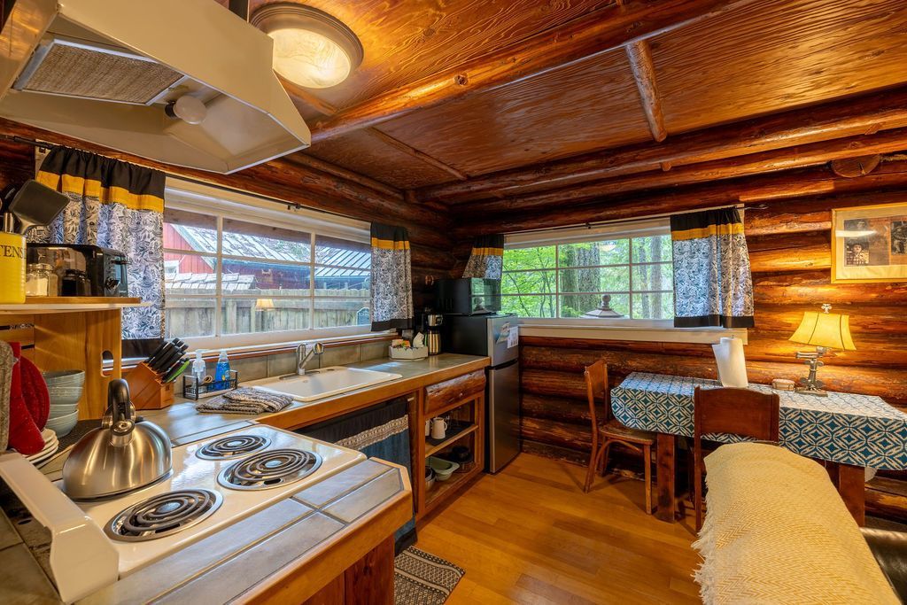 Rustic cabin kitchen with wood walls, a stove, and a small dining table with a cozy atmosphere.