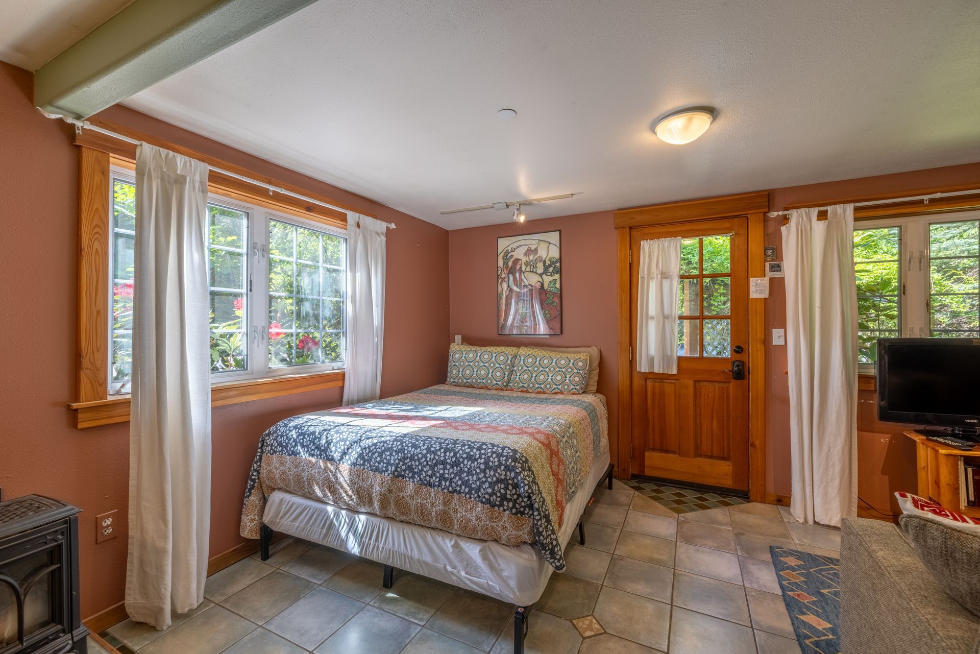 A bedroom with a bed , stove , window and door.