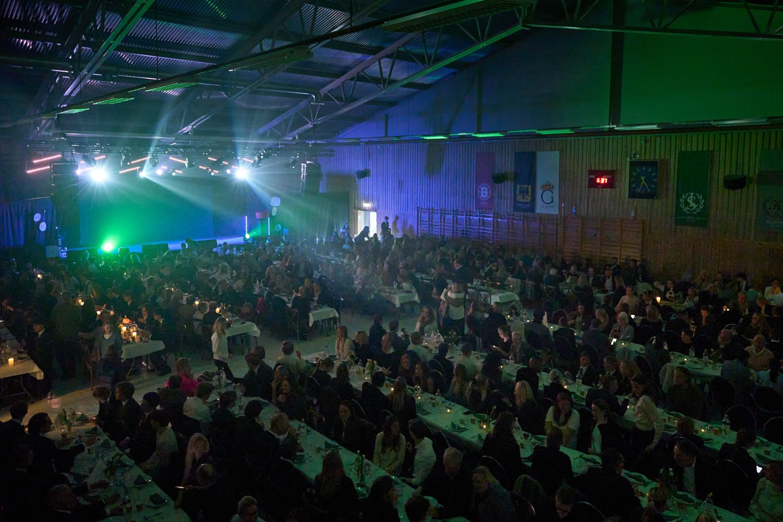 Fullsatt inomhuskonsertsal med gröna scenljus och sittande publik