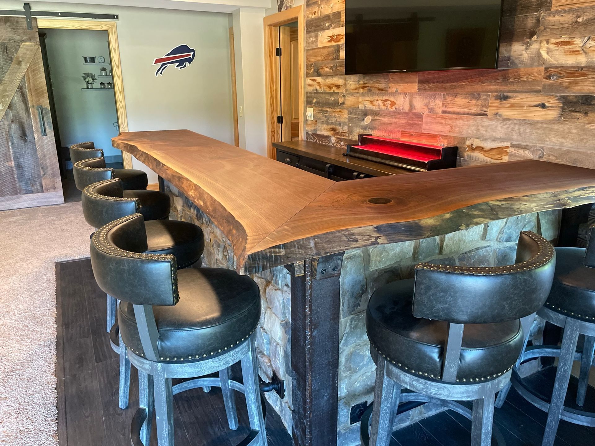 A bar with stools and a television on the wall.