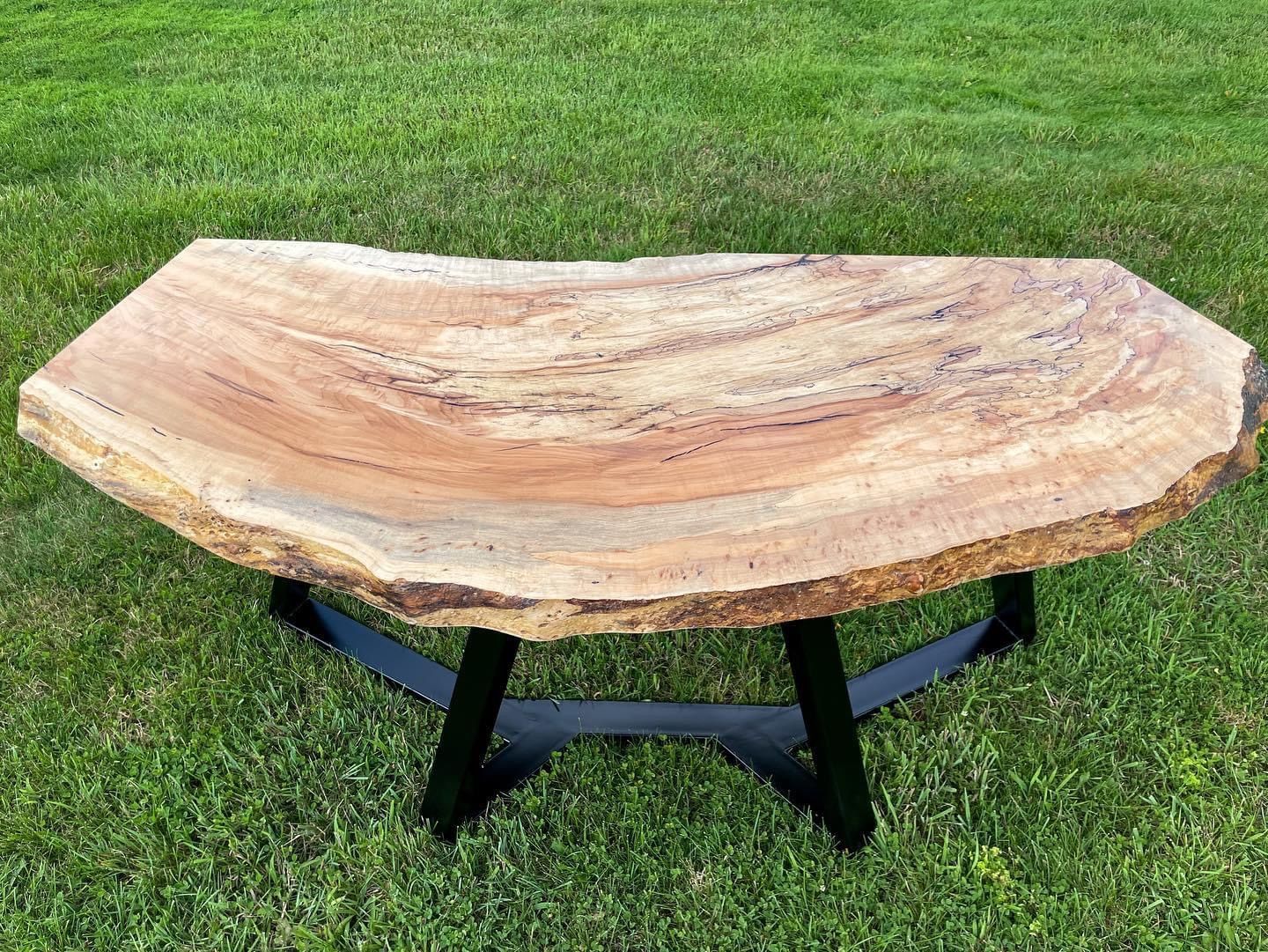 A wooden table is sitting on top of a lush green field.