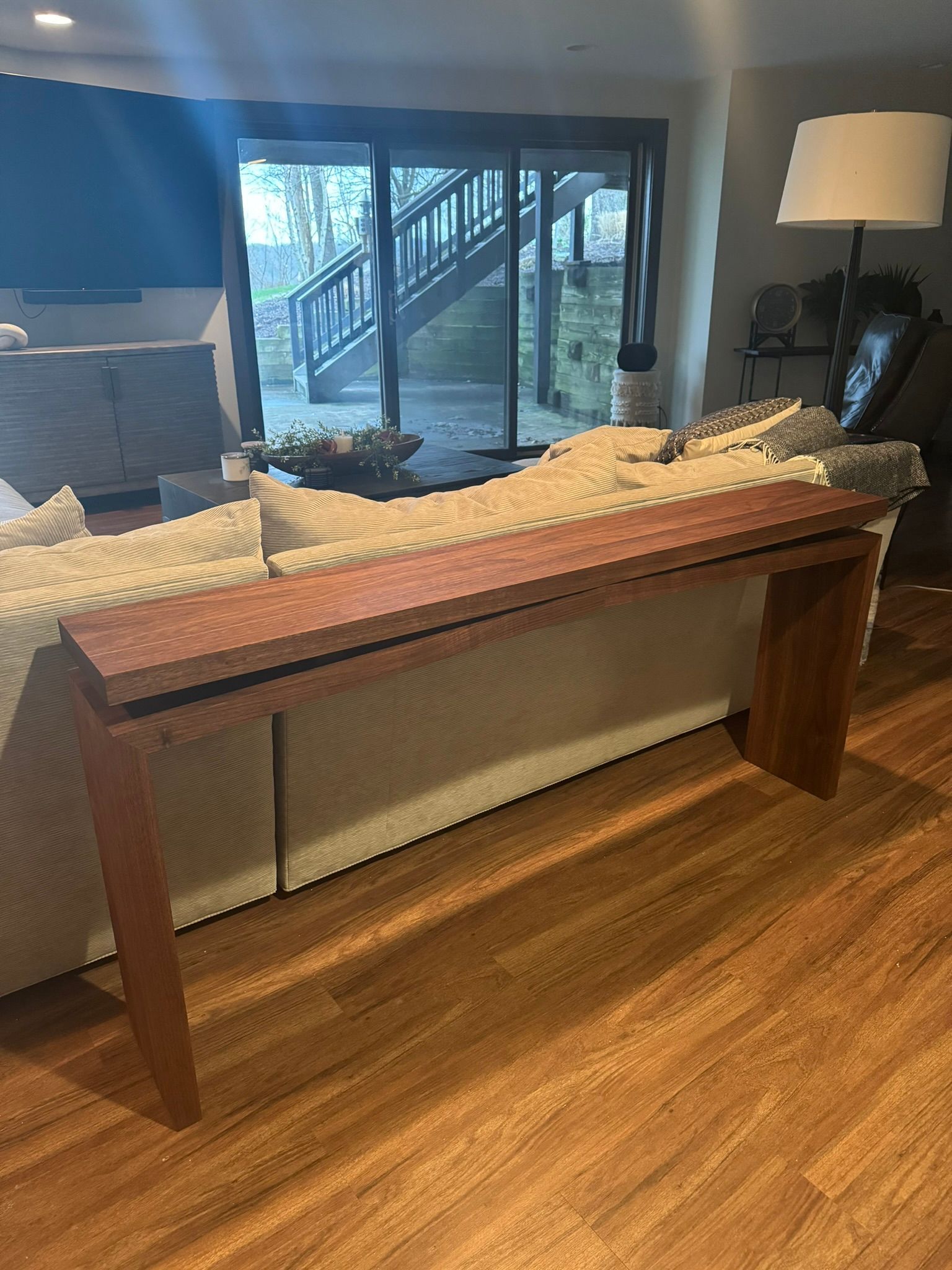 A small wooden table with white legs is sitting on a wooden floor.