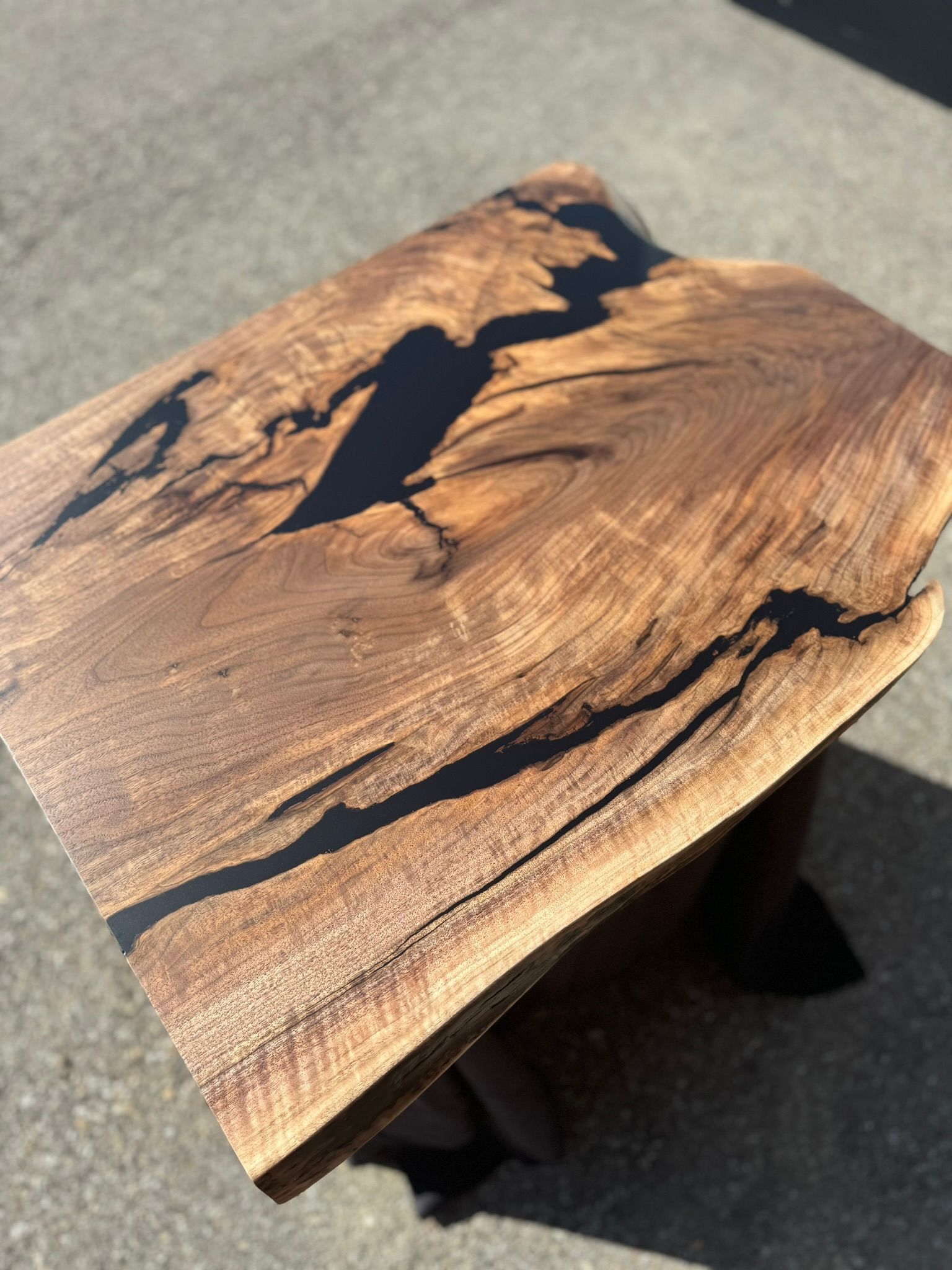 A piece of wood with black resin on it is sitting on the ground.
