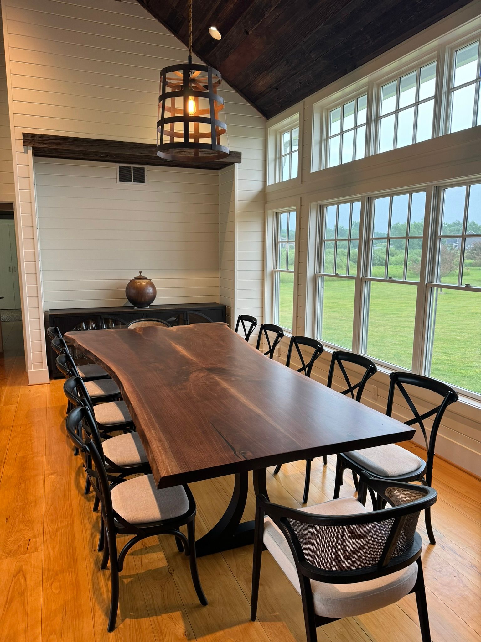 A long wooden table with chairs in a room with a lot of windows.