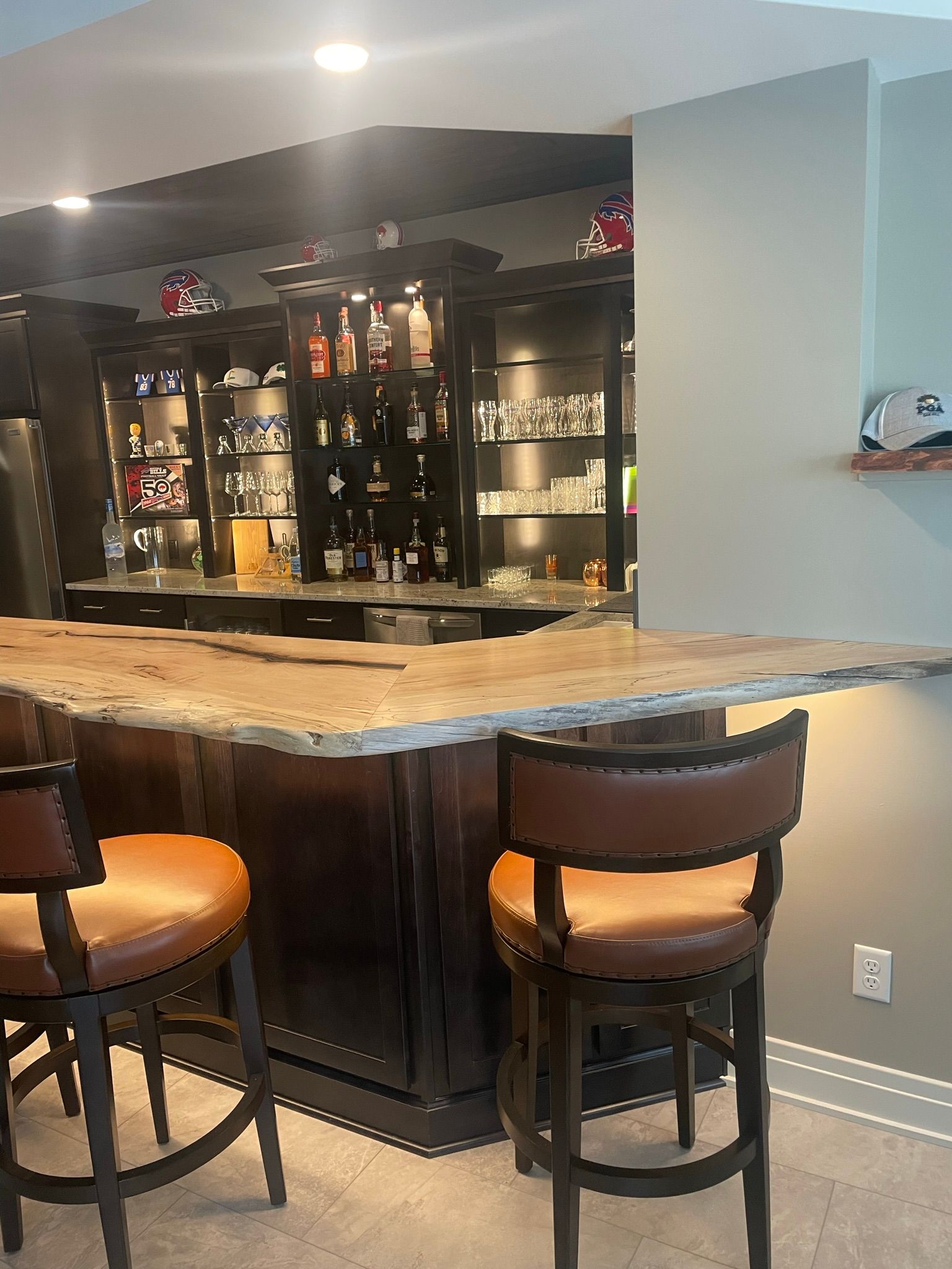 A bar with a wooden counter top and two chairs in a basement.